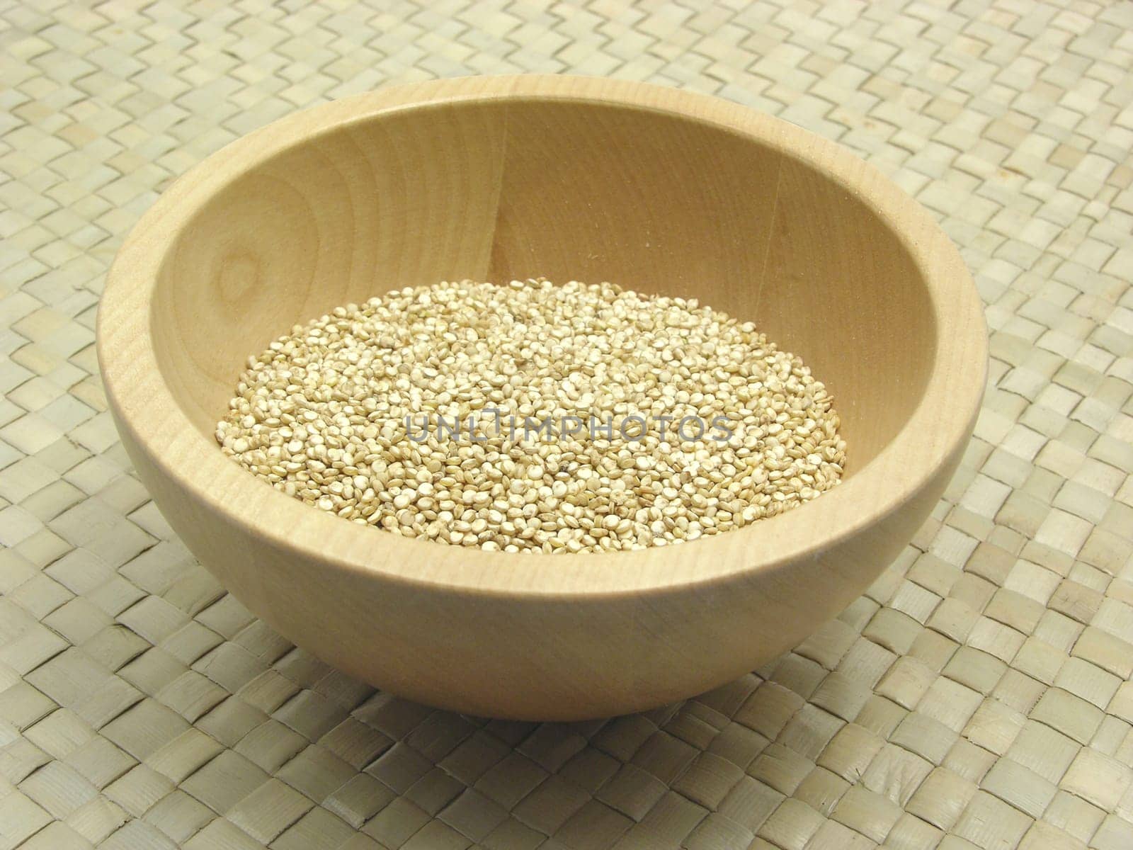Wooden bowl with quinoa on rattan base