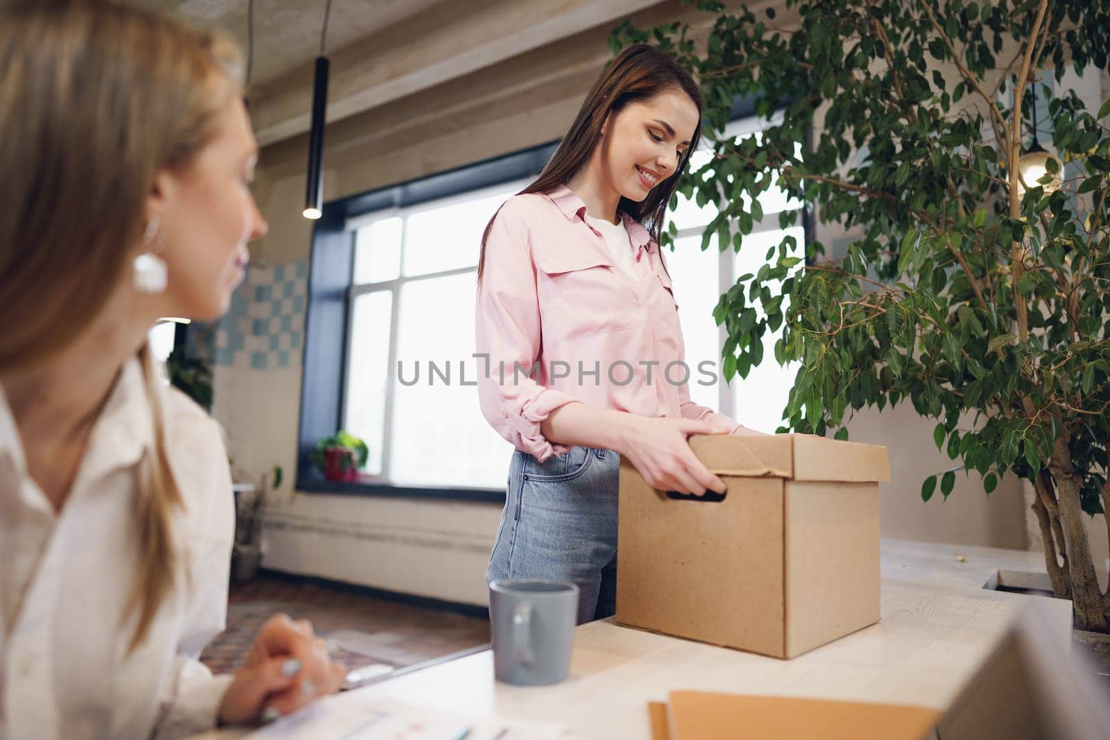 Young businesswoman holding box of personal belongings about to leave the office after quitting job