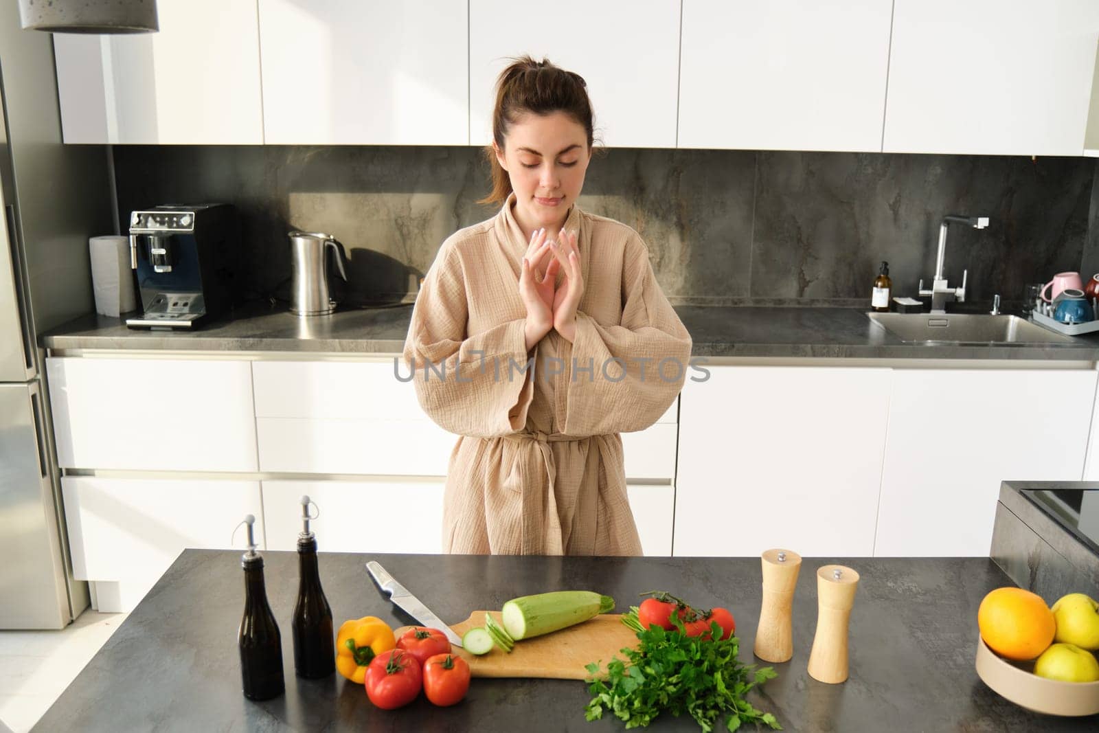 Portrait of excited woman looks thoughtful at chopping board with zucchini, vegetables, preparing healthy salad, making vegetarian meal, choosing what to have for dinner, standing in kitchen.