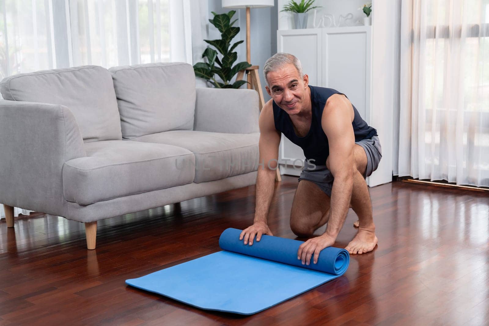 Active and sporty senior man preparing fitness mat. Clout by biancoblue