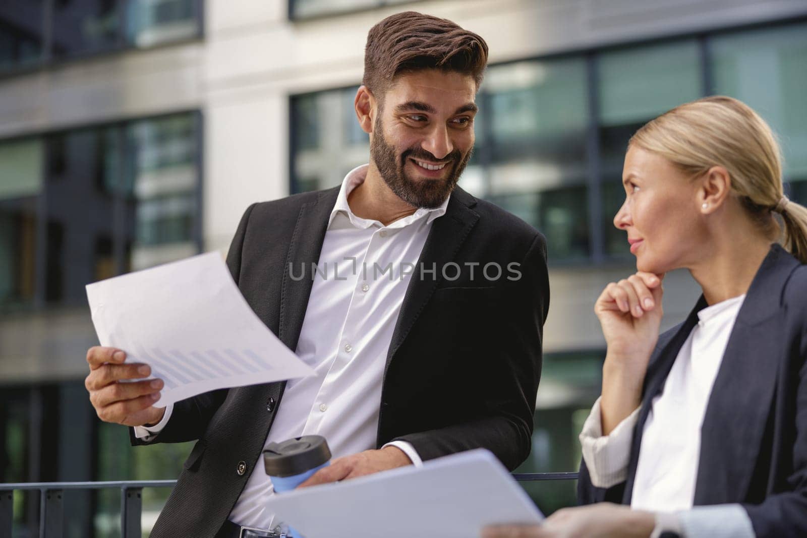 Business colleagues working with documents standing outside of office and drink coffee