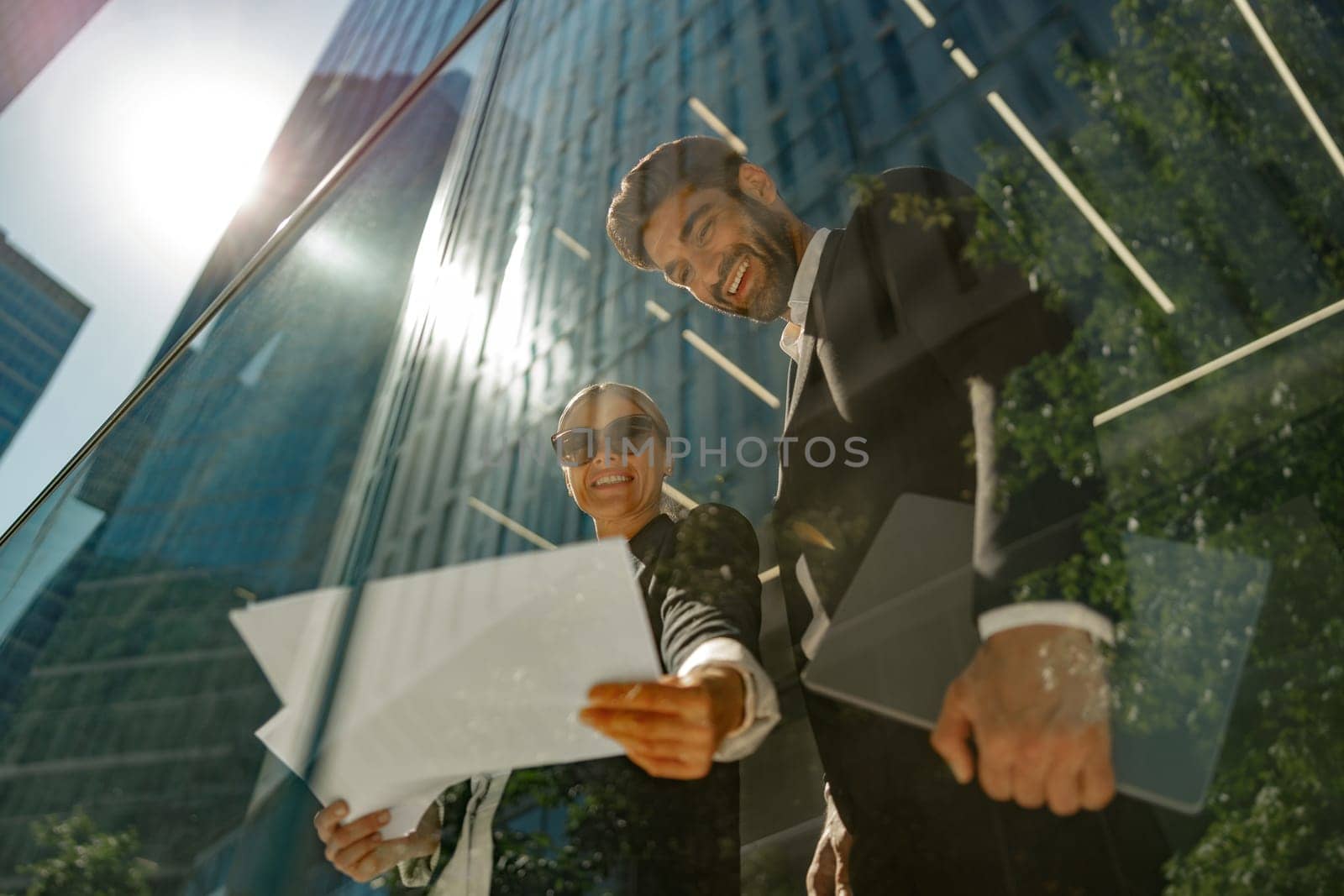 Bottom view of business partners working with documents standing outside of office and drink coffee by Yaroslav_astakhov