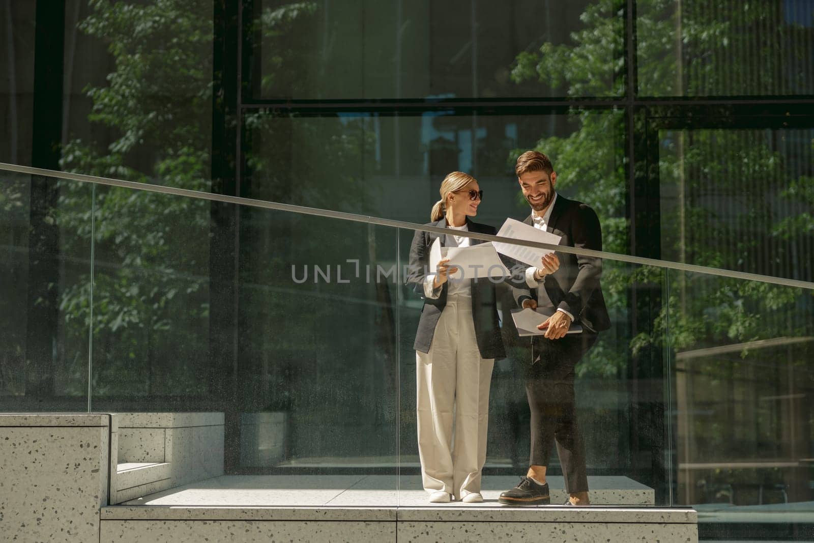 Business colleagues working with documents while standing on background of modern office building