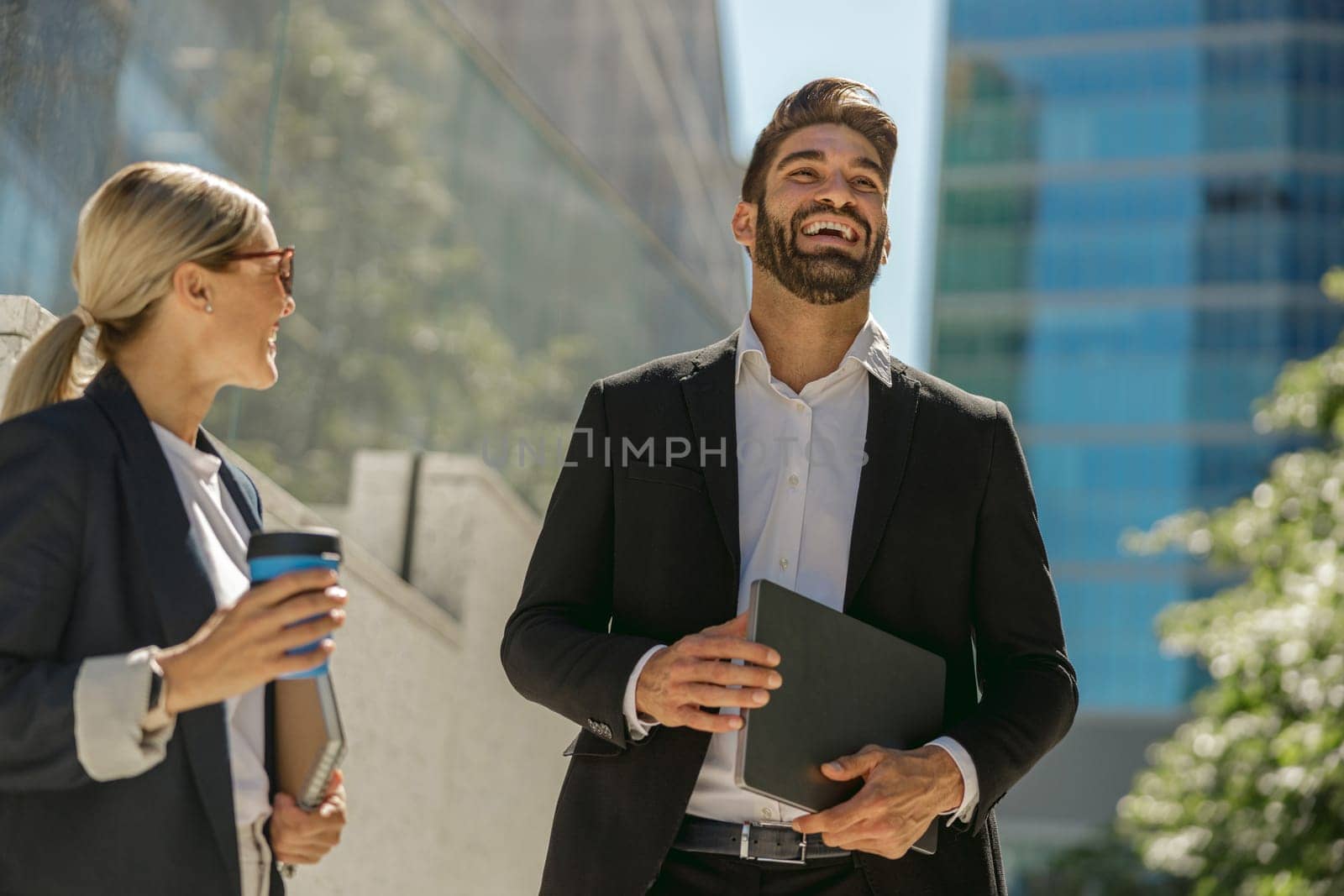 Two managers talking during break standing on background of modern city skyscrapers