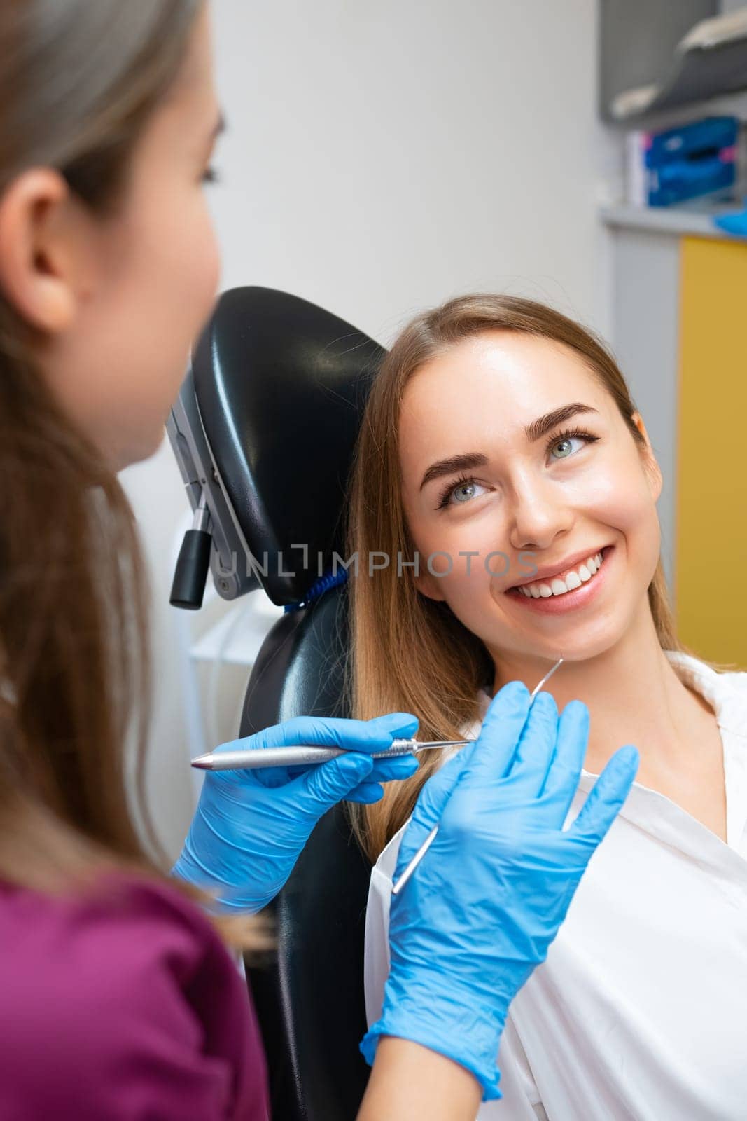 Portrait of young caucasian woman with perfect smile in dental clinic, vertical photo