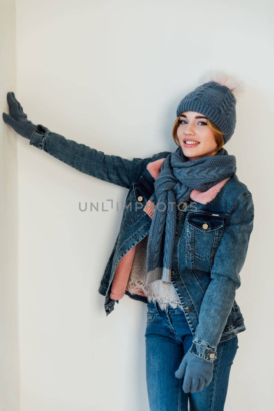 woman with a warm hat with a scarf in winter clothes stands on a white background