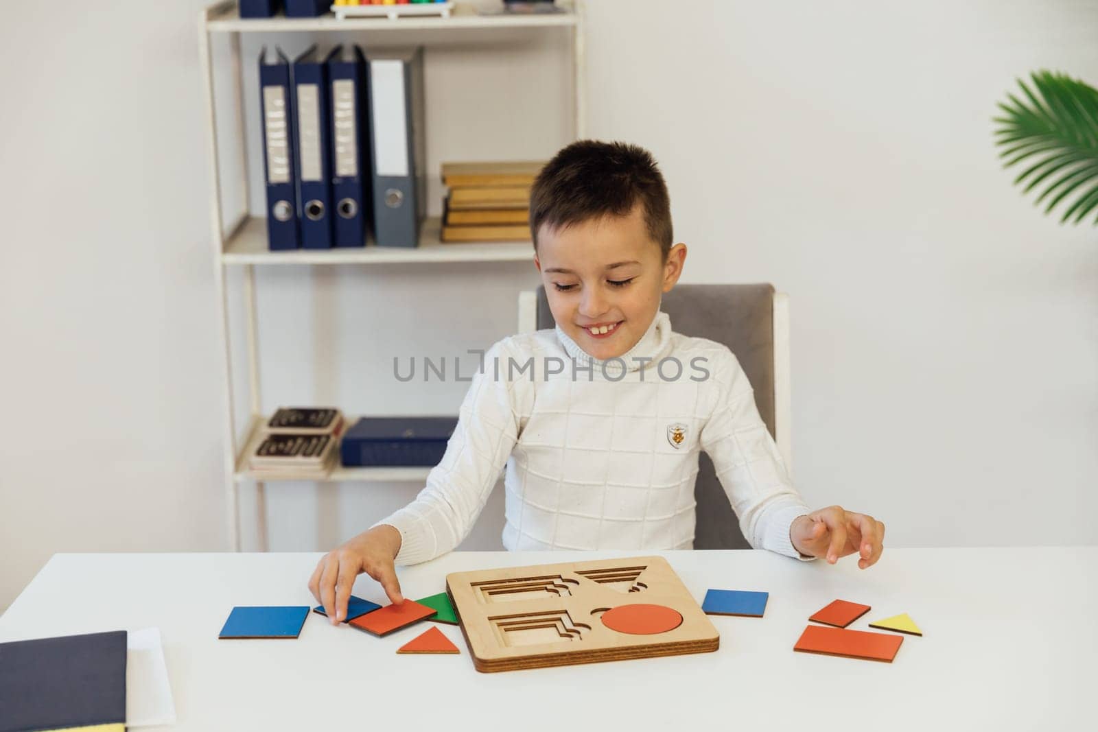 boy sits at the table with an educational game in the office