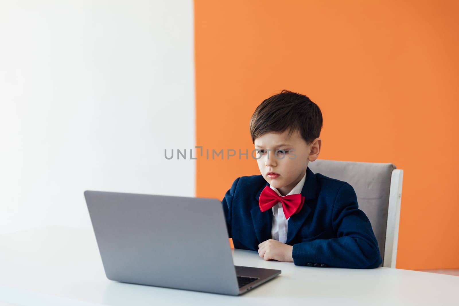 schoolboy boy sitting at a laptop at desk in a school in a classroom online education room