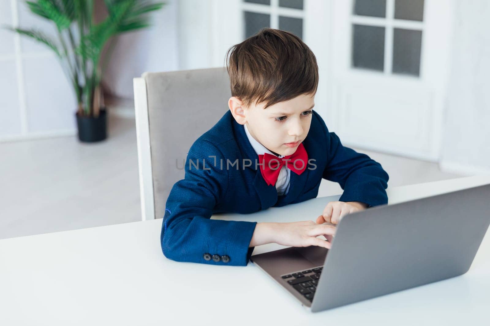 school student sitting at laptop at a desk in a classroom online education room