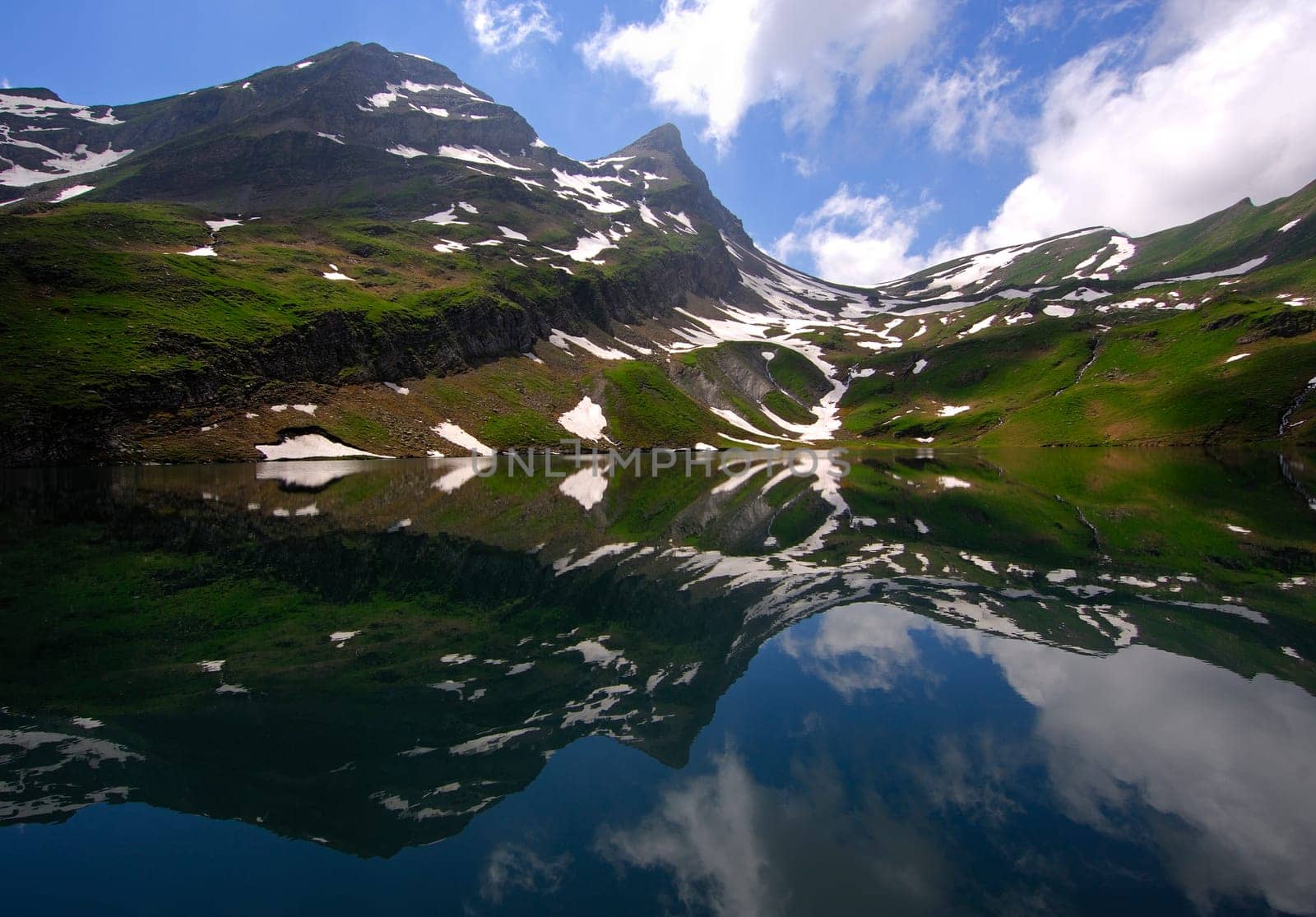 Reflection of peaks,snow and clouds in a mountain lake