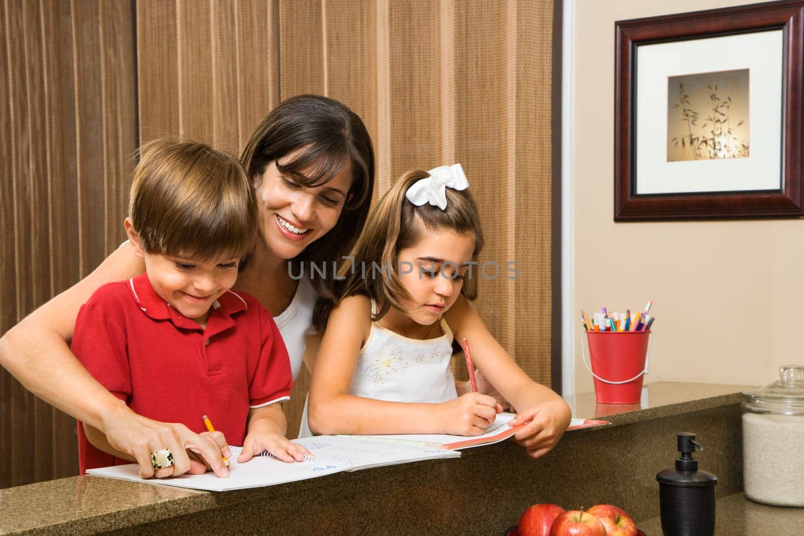 Hispanic mother helping children with homework.