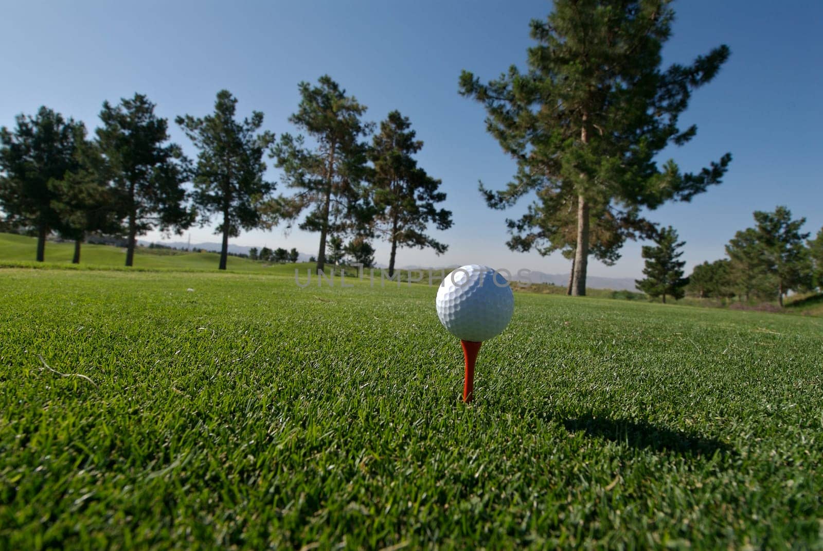 Golf ball on red tee with scenic background