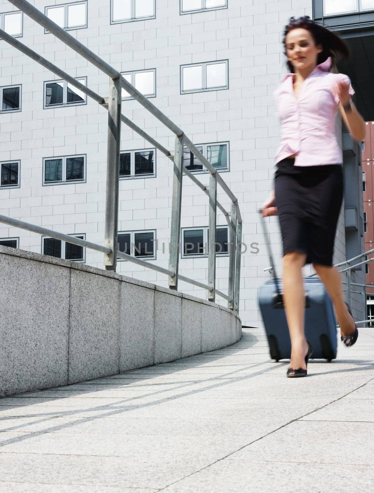 business woman rushes out of the office with trolley bag