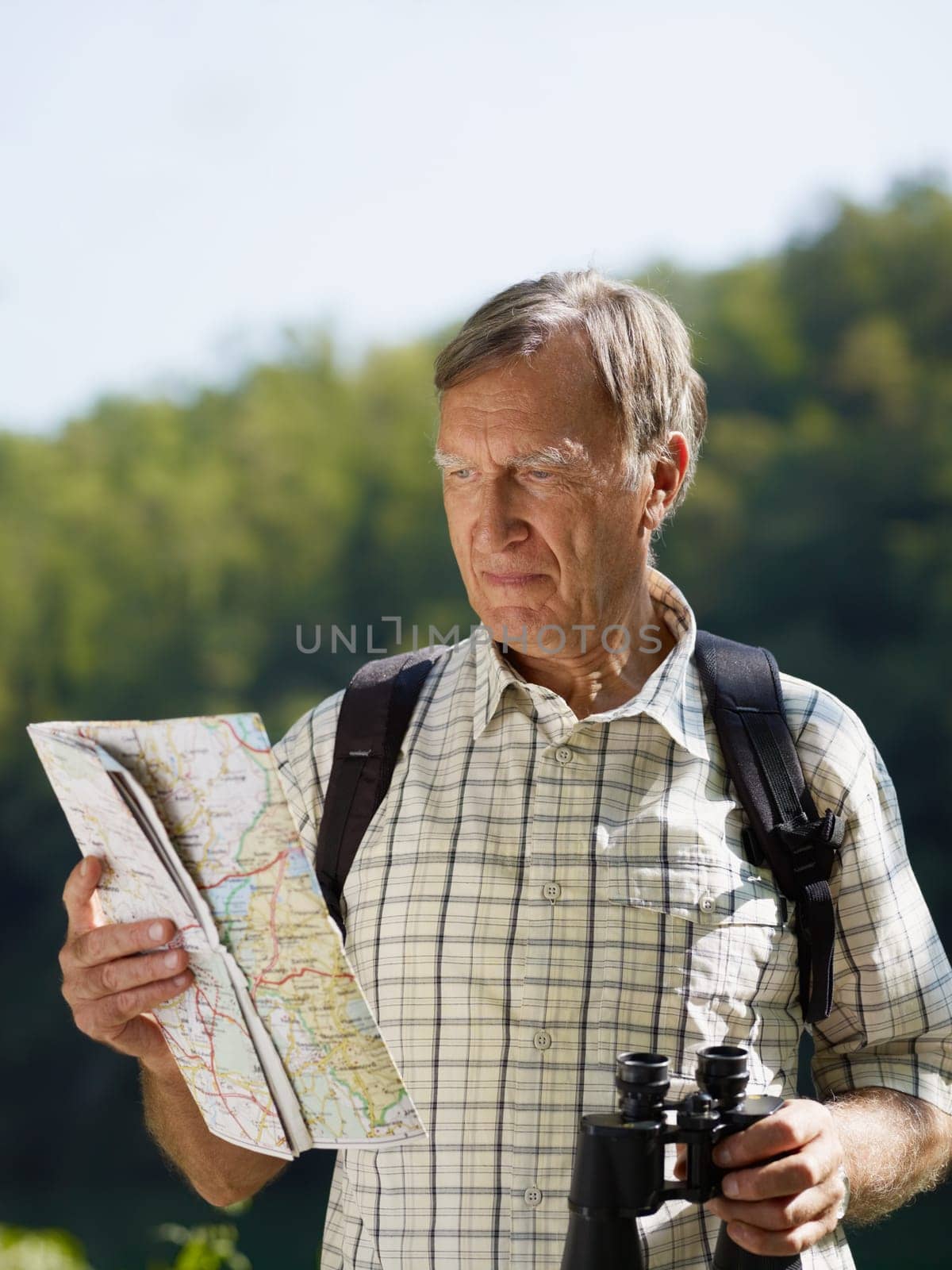 senior hiker holding map and binoculars. Copy space