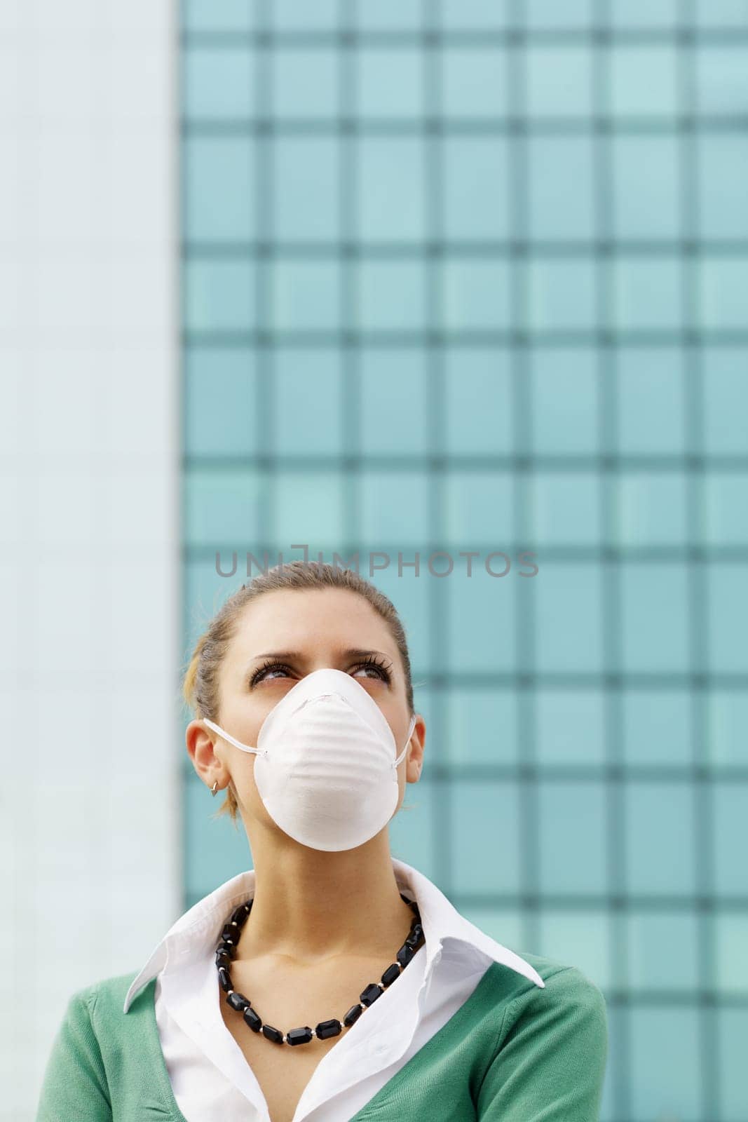 woman standing against office building and wearing protective mask. Copy space