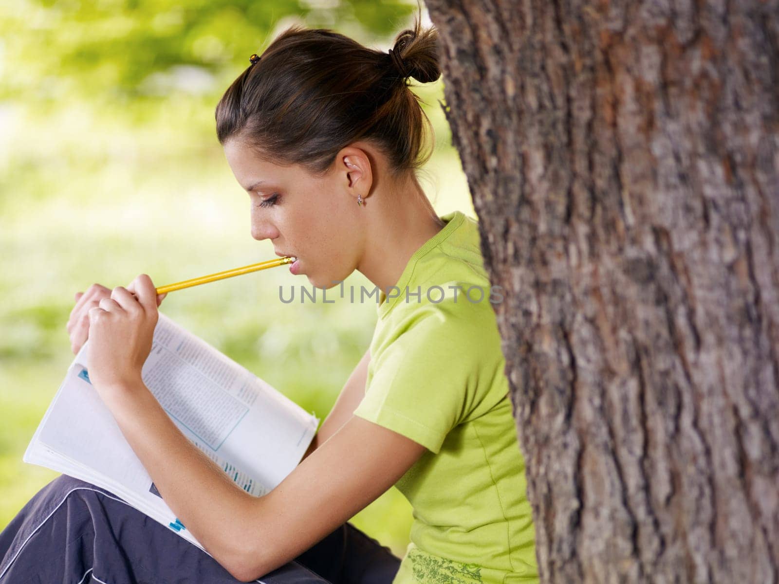 young woman studying outdoors and leaning on tree. Copy space
