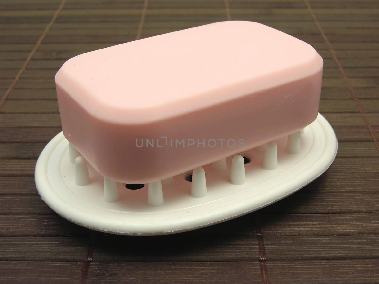 Pink soap on soap tray against brown background