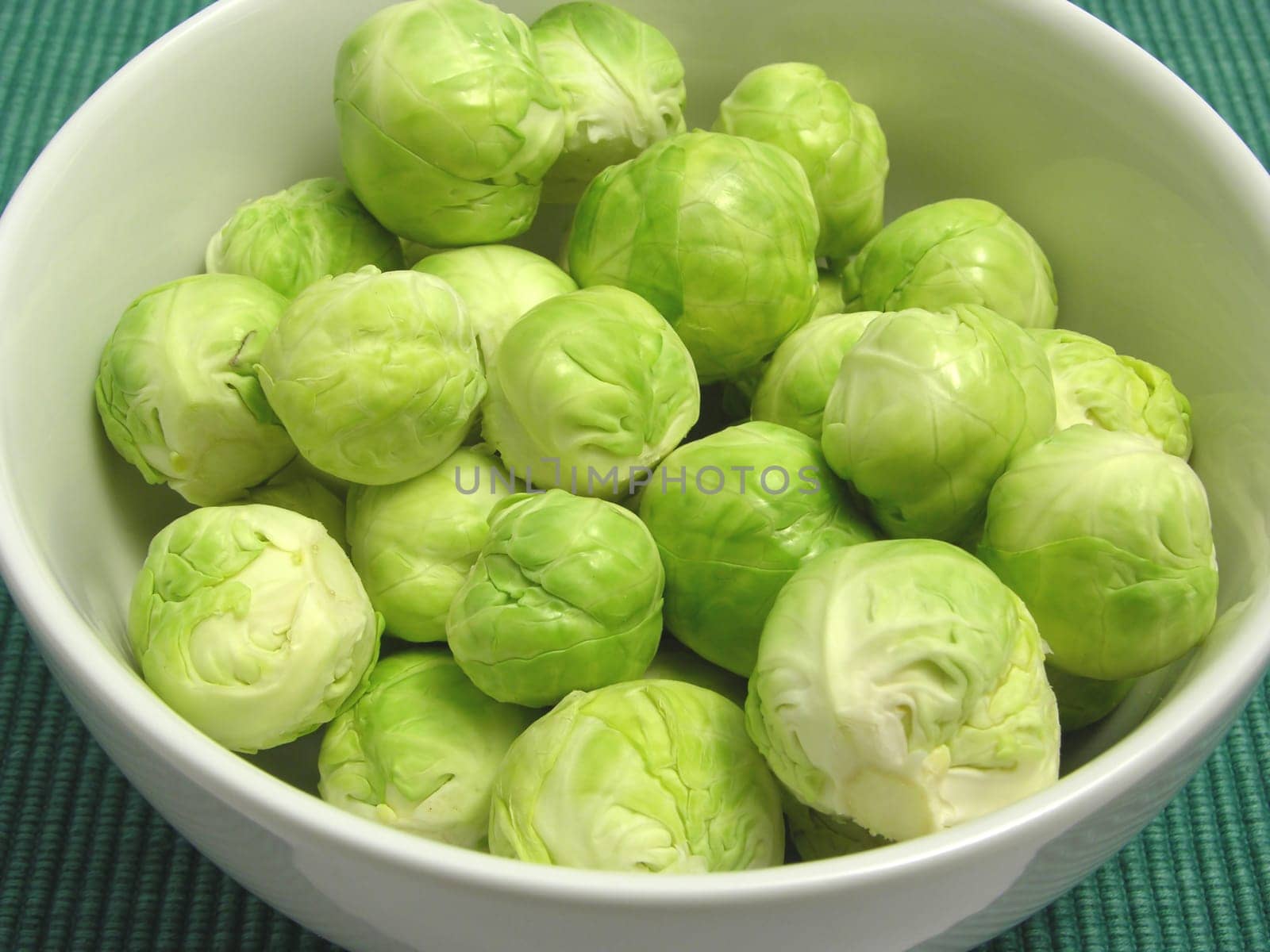 Brussels sprouts in white bowl and green placemat