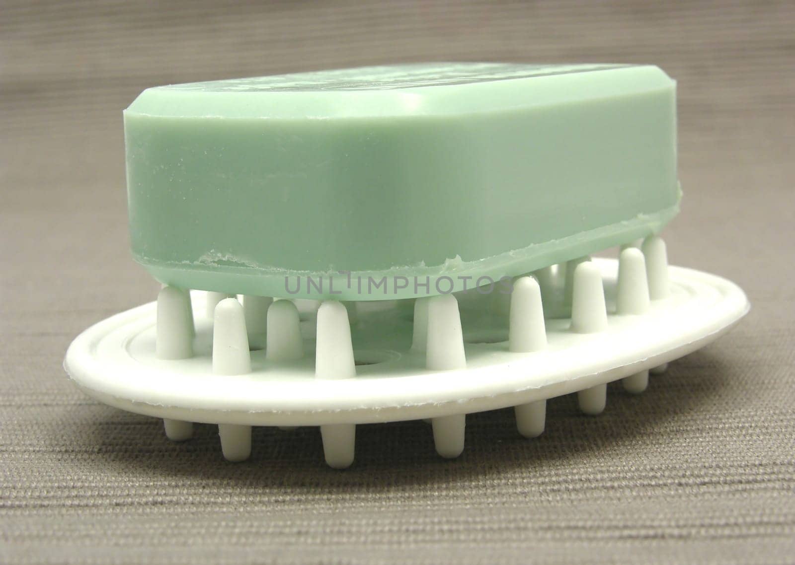 Green soap on soap tray against gray background