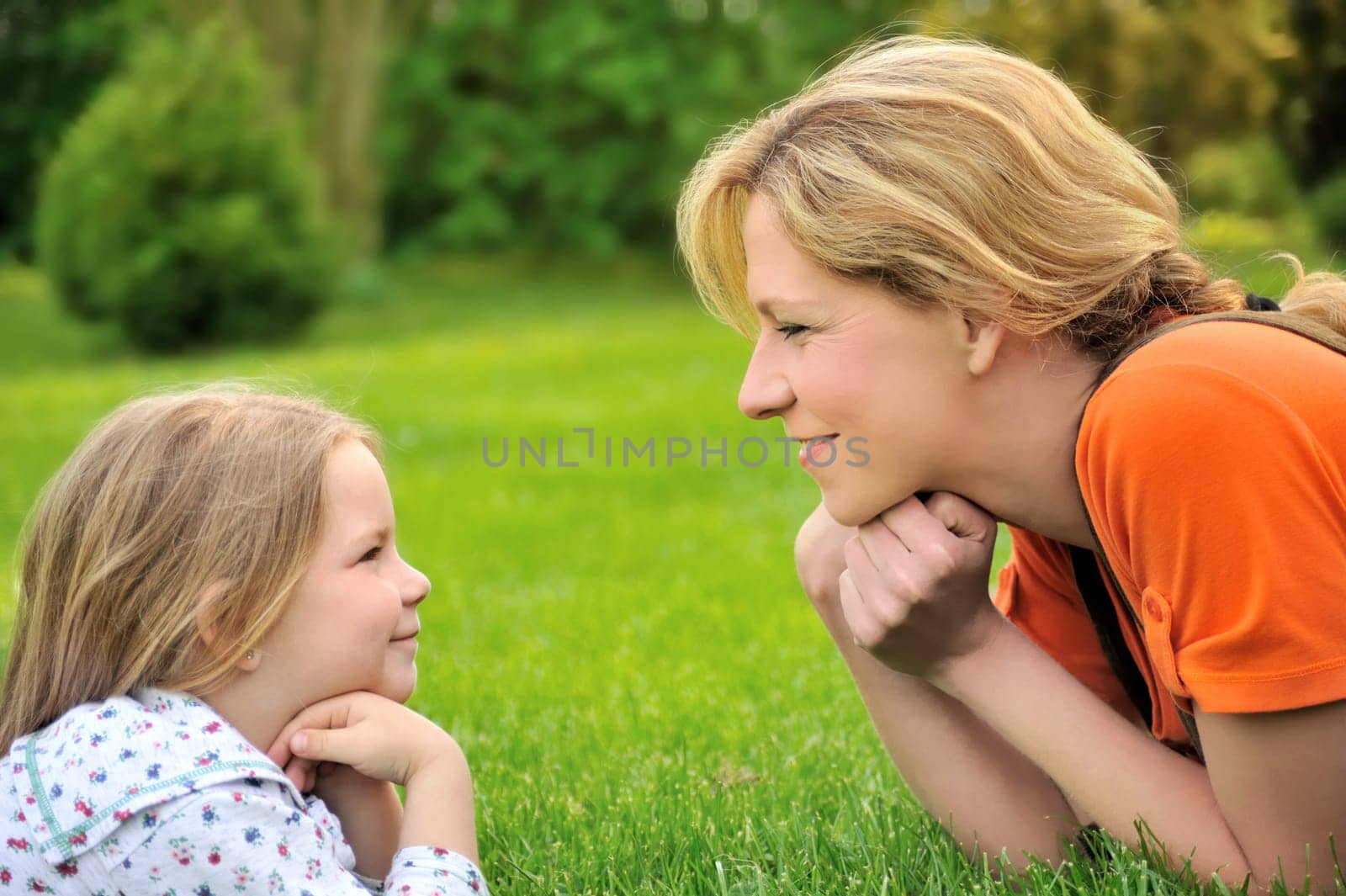 Young mother and daughter laying on the grass