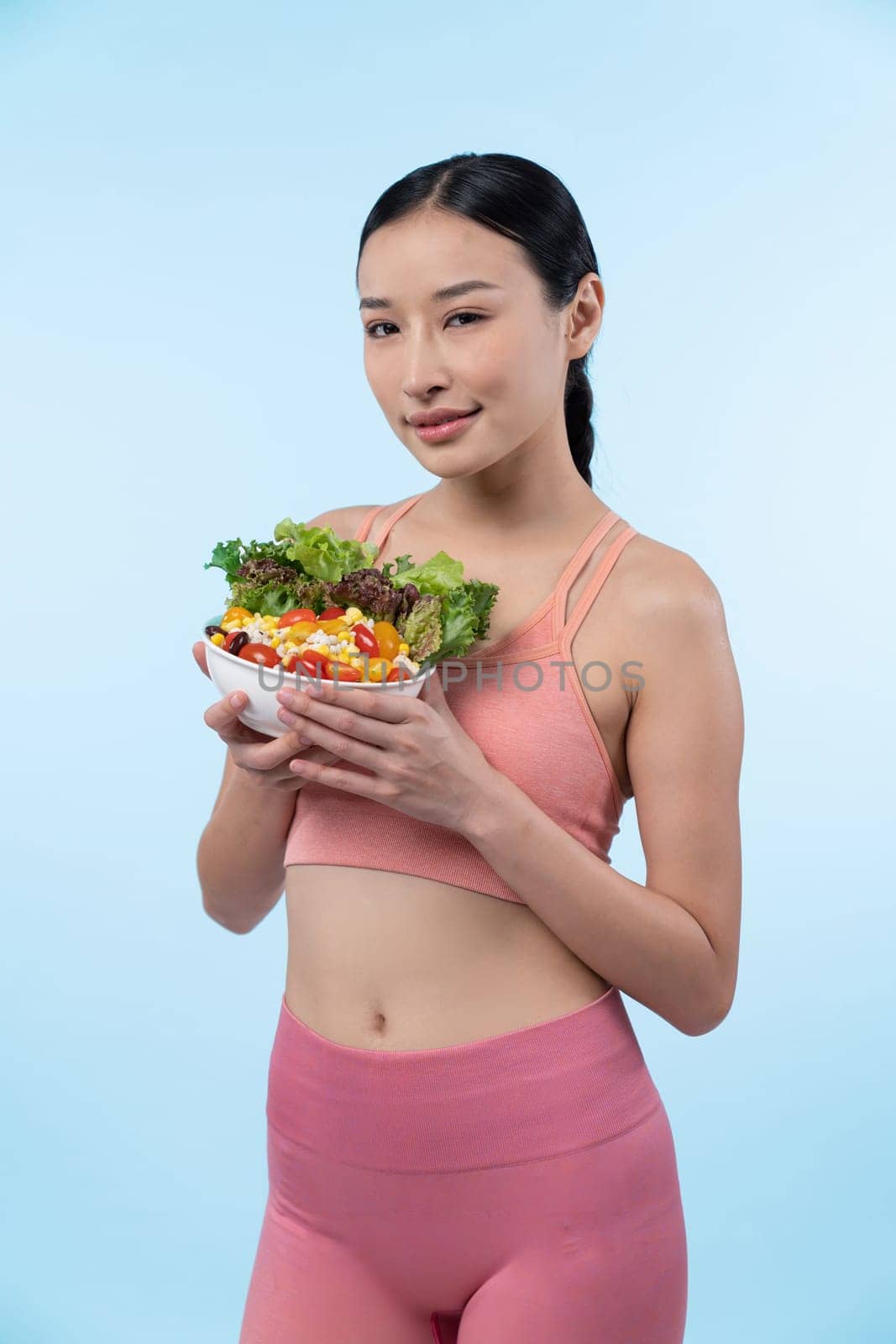 Asian woman in sportswear holding salad bowl on isolated background. Vigorous by biancoblue