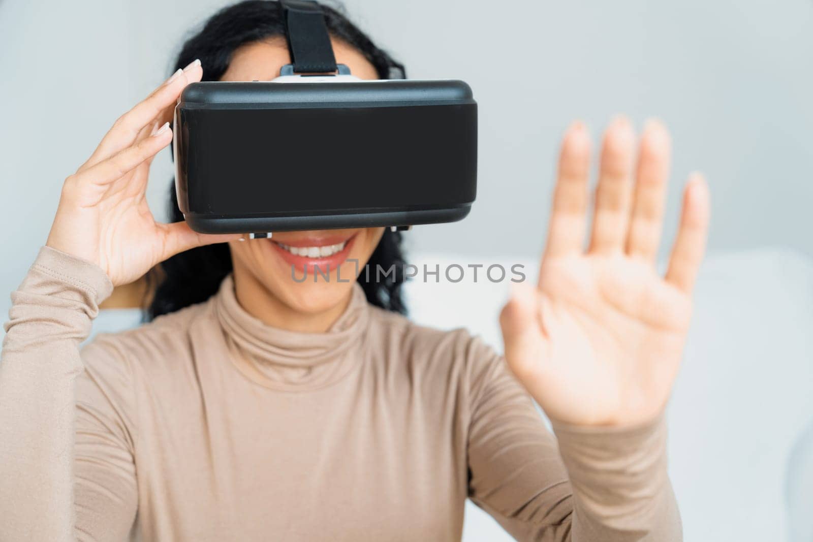 Young woman using virtual reality VR goggle at home for crucial experience by biancoblue