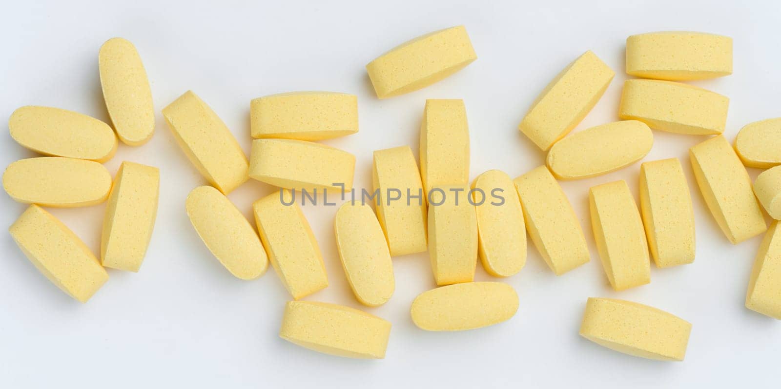 Yellow oval tablets on a white background, top view
