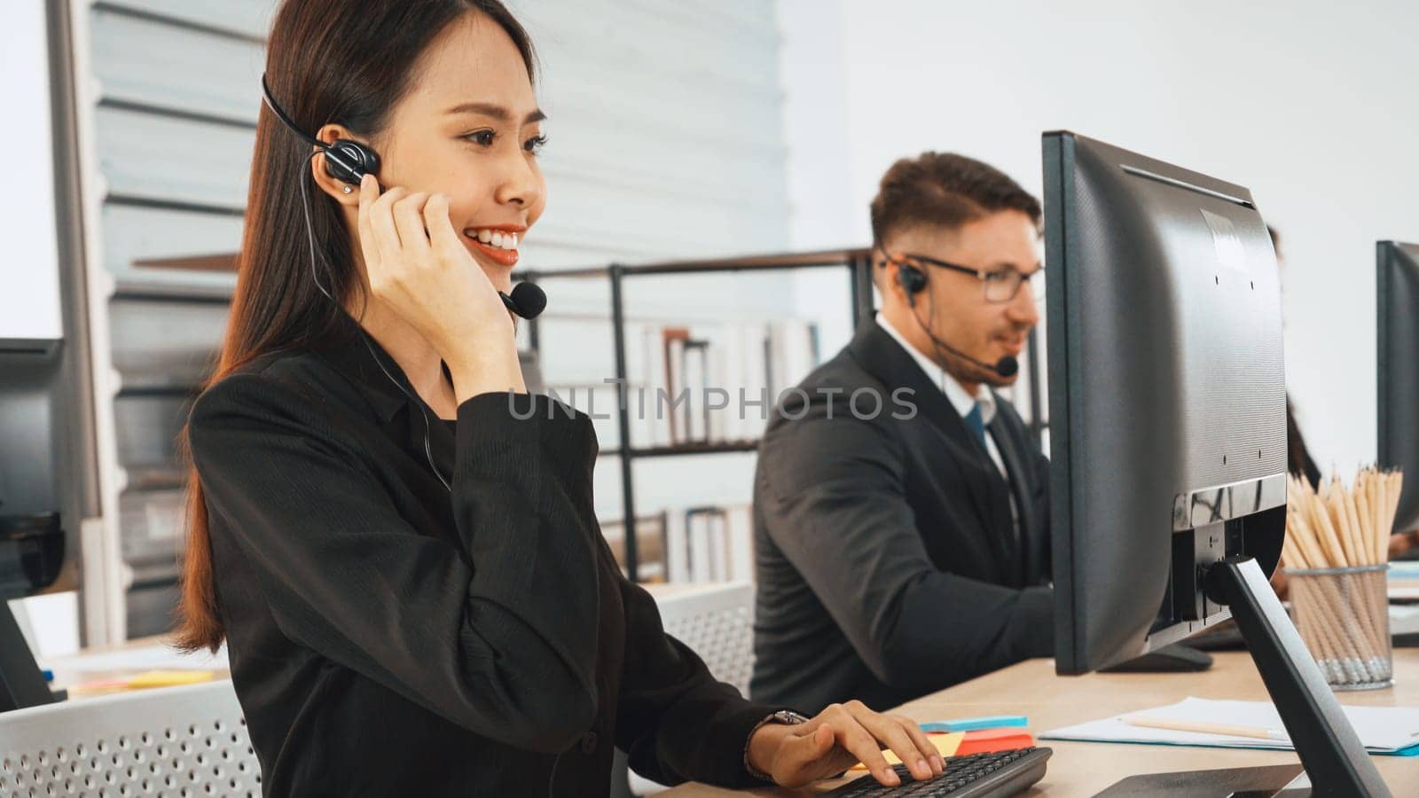 Business people wearing headset working in office to support remote customer or colleague. Call center, telemarketing, customer support agent provide service on telephone video conference call. Jivy