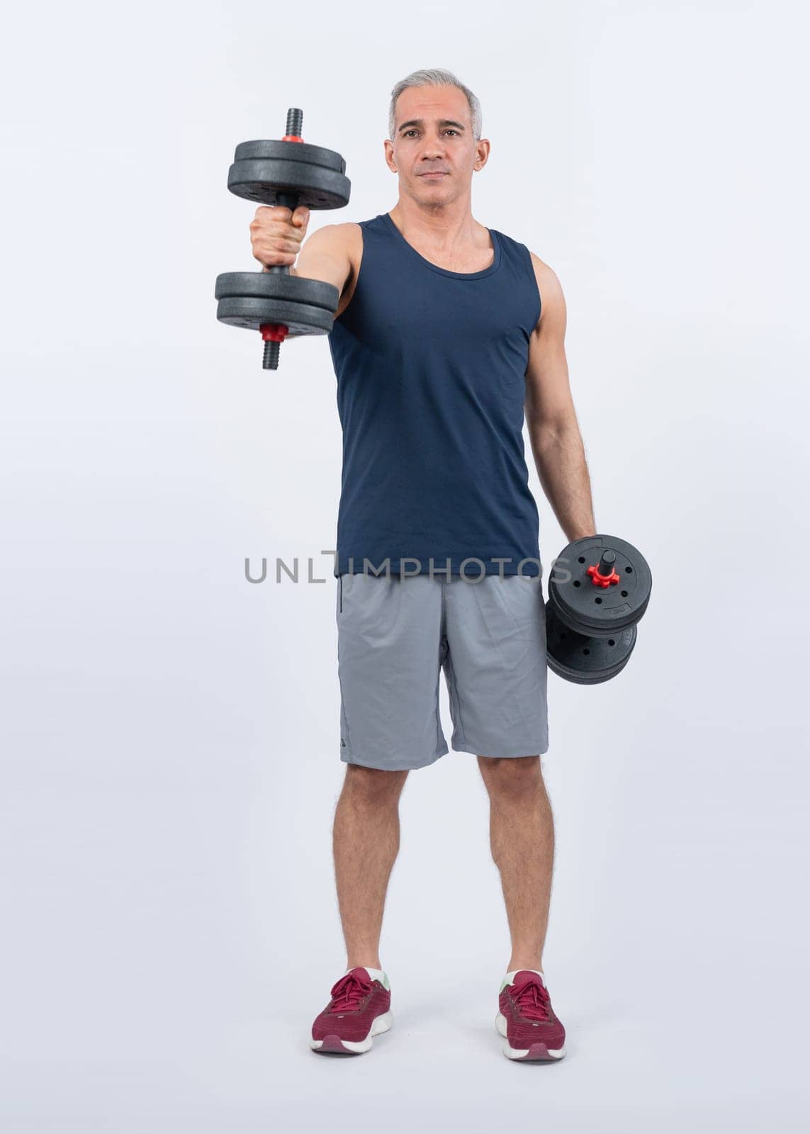 Full body length shot active and sporty senior man lifting dumbbell. Clout by biancoblue