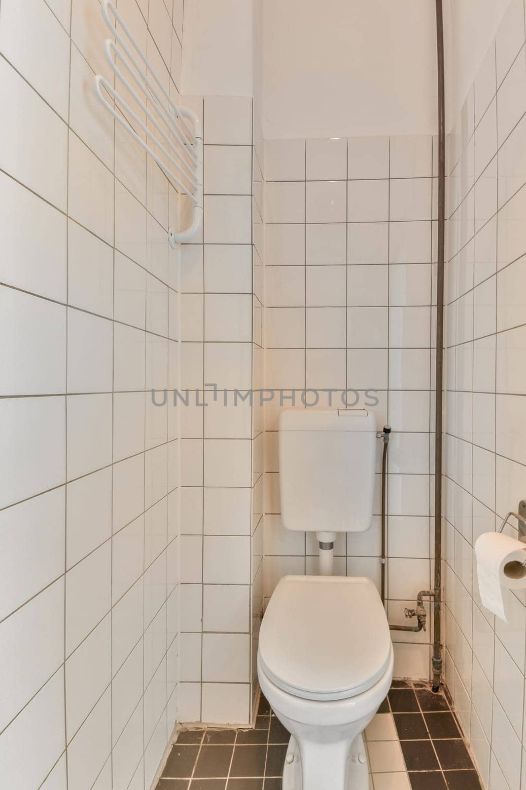 a white toilet in a small bathroom with tiled walls and black tiles on the floor, there is a mirror above it