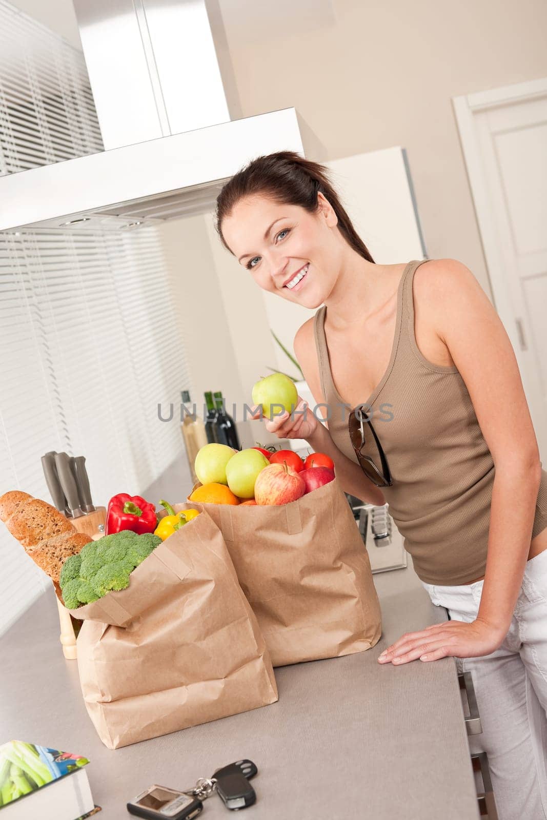 Young smiling woman with groceries in the kitchen