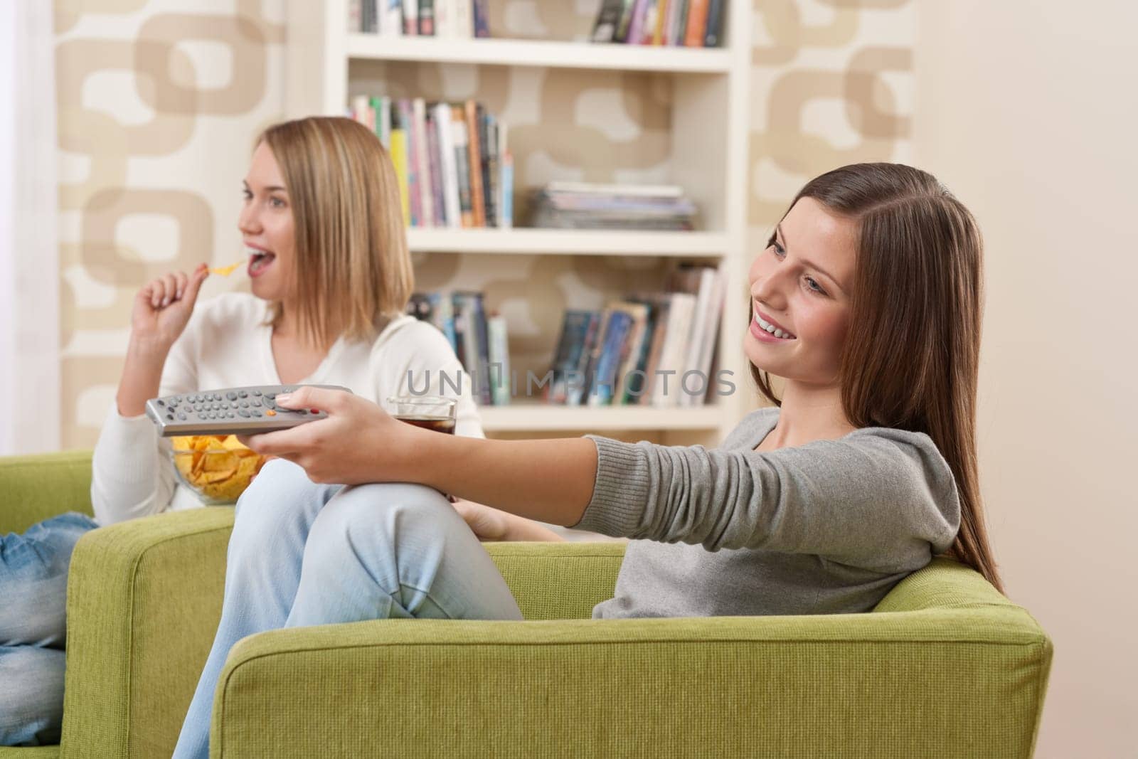 Two female teenager watching television