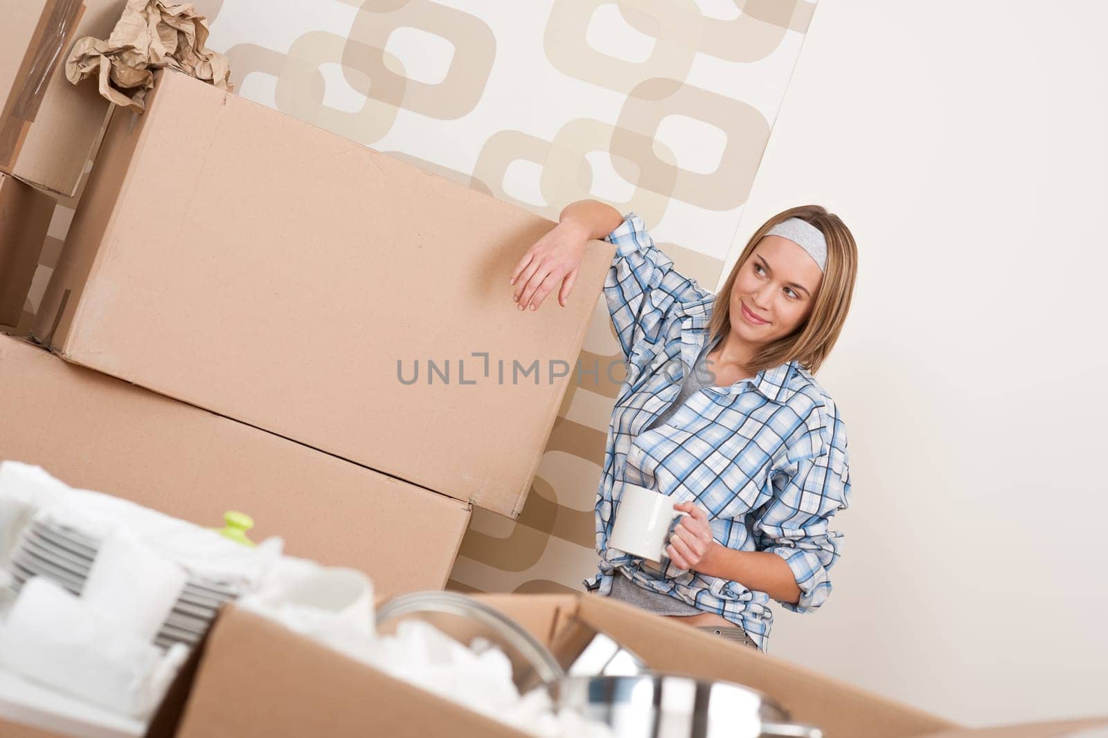 Moving house Woman unpacking box with kitchen dishes