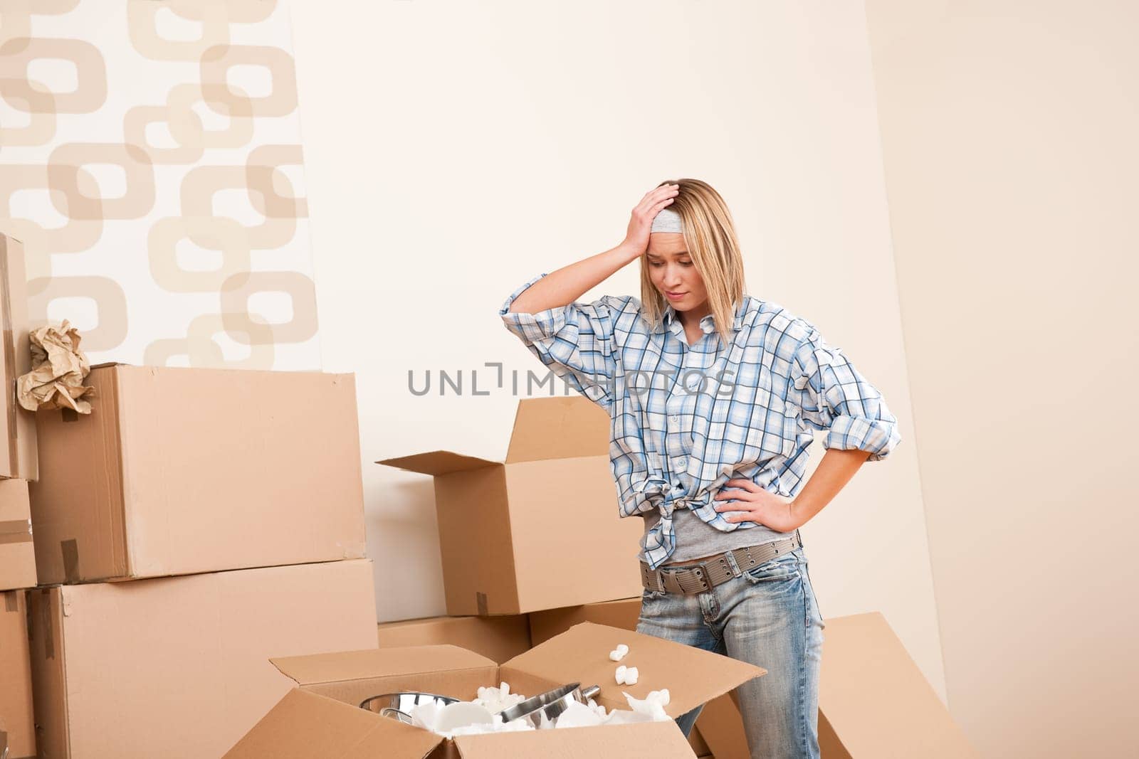 Moving house Woman unpacking box with kitchen dishes