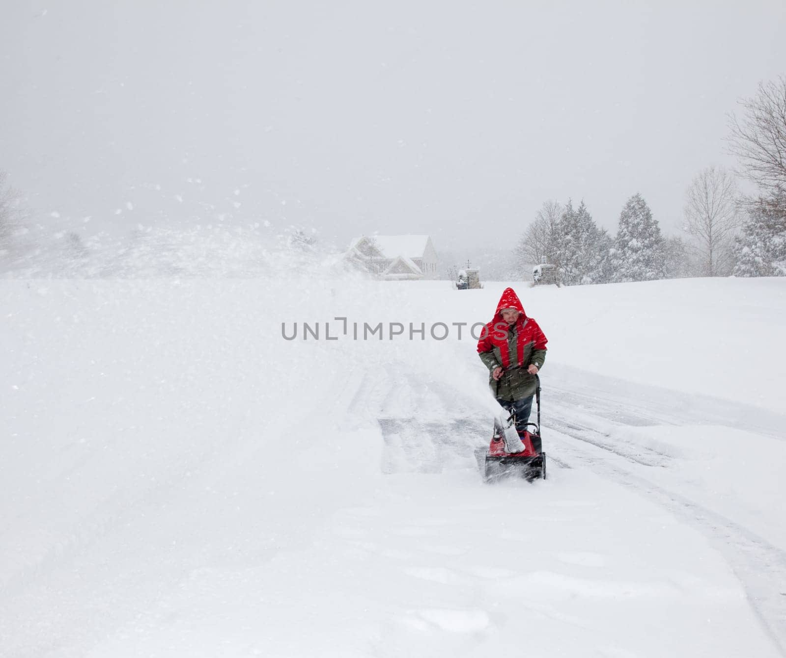 Man using snow blower on snowy drive