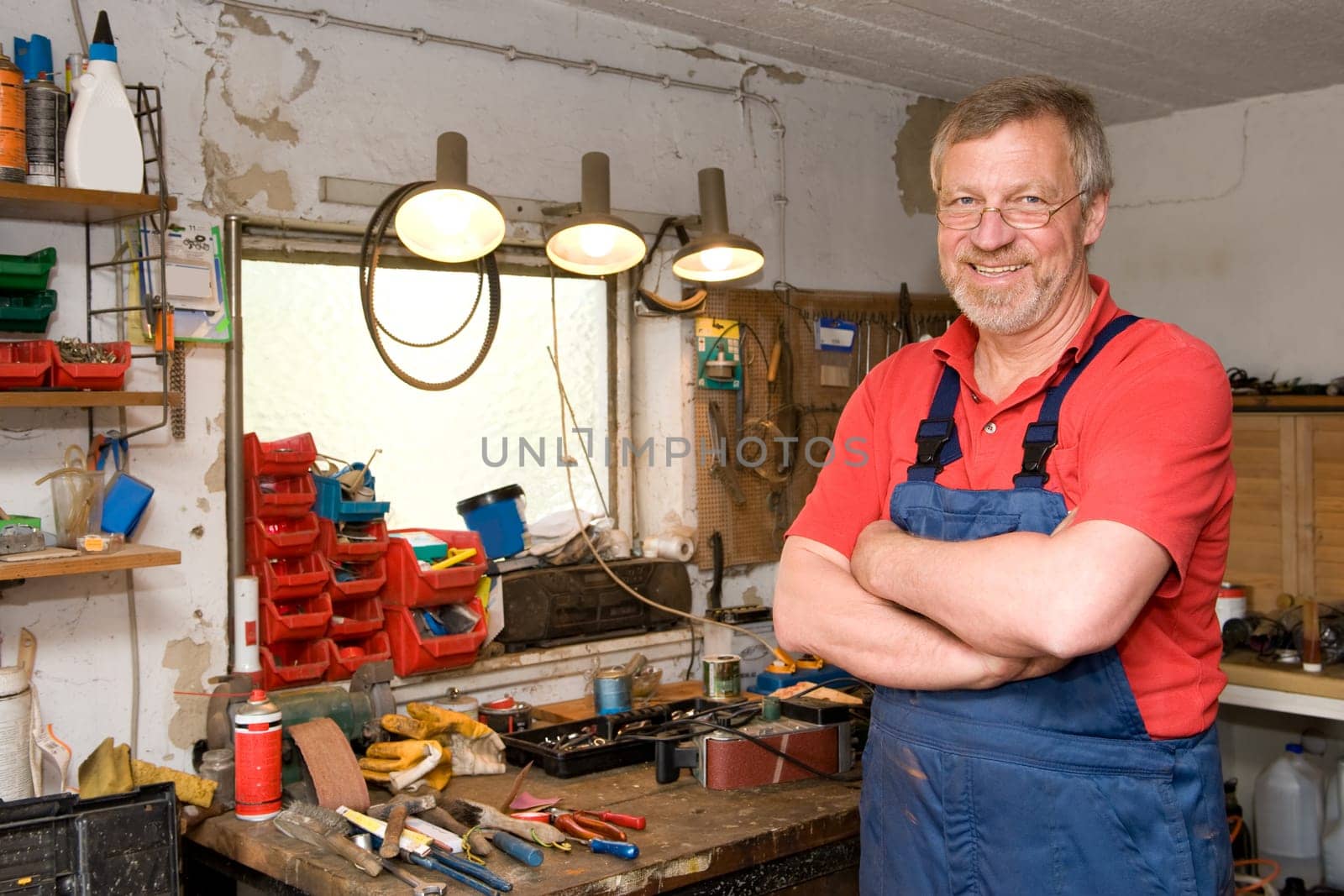 Active pensioner in a blue suit and crossed arms in his garage