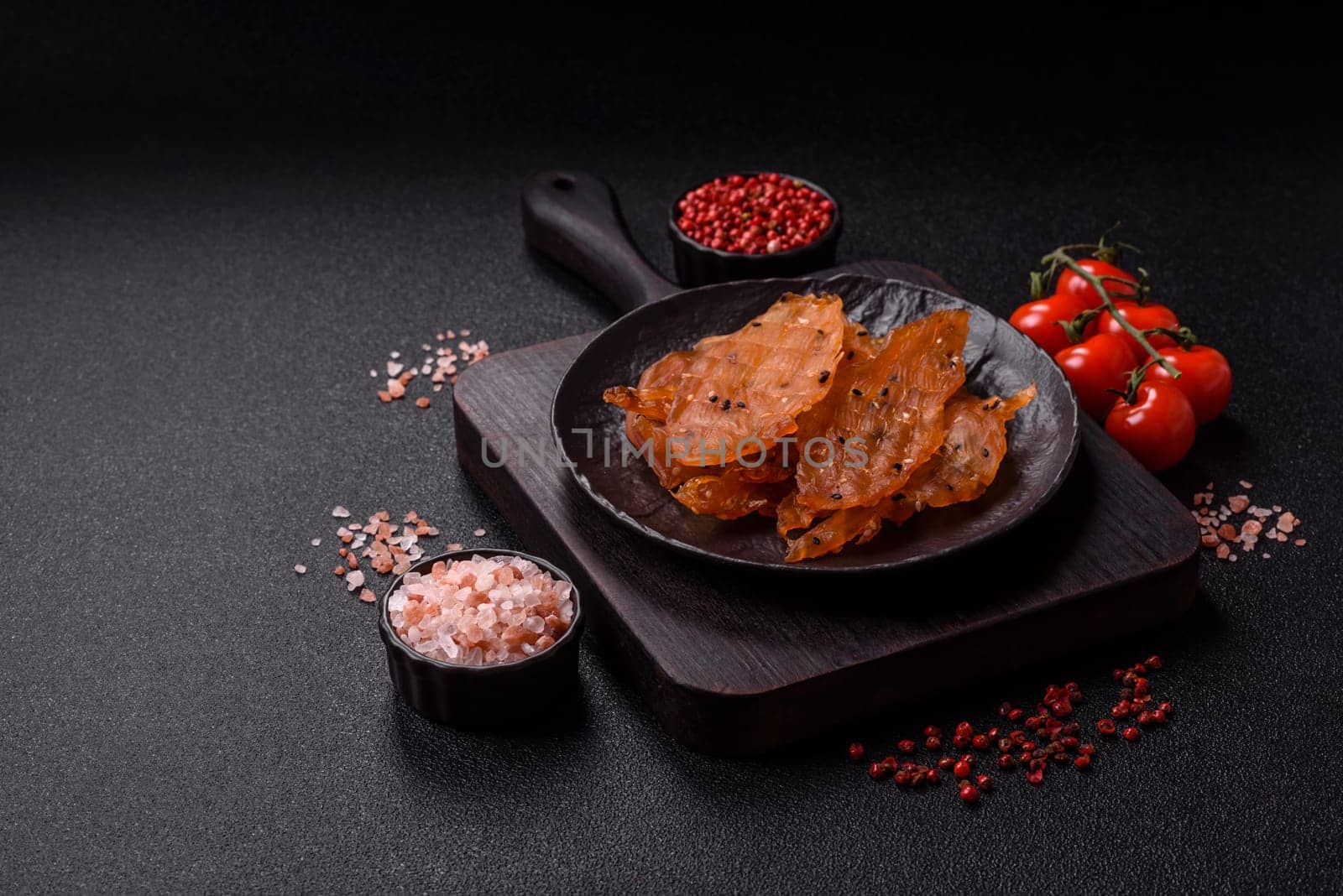 Jerky, dried chicken meat with salt and spices on a dark concrete background