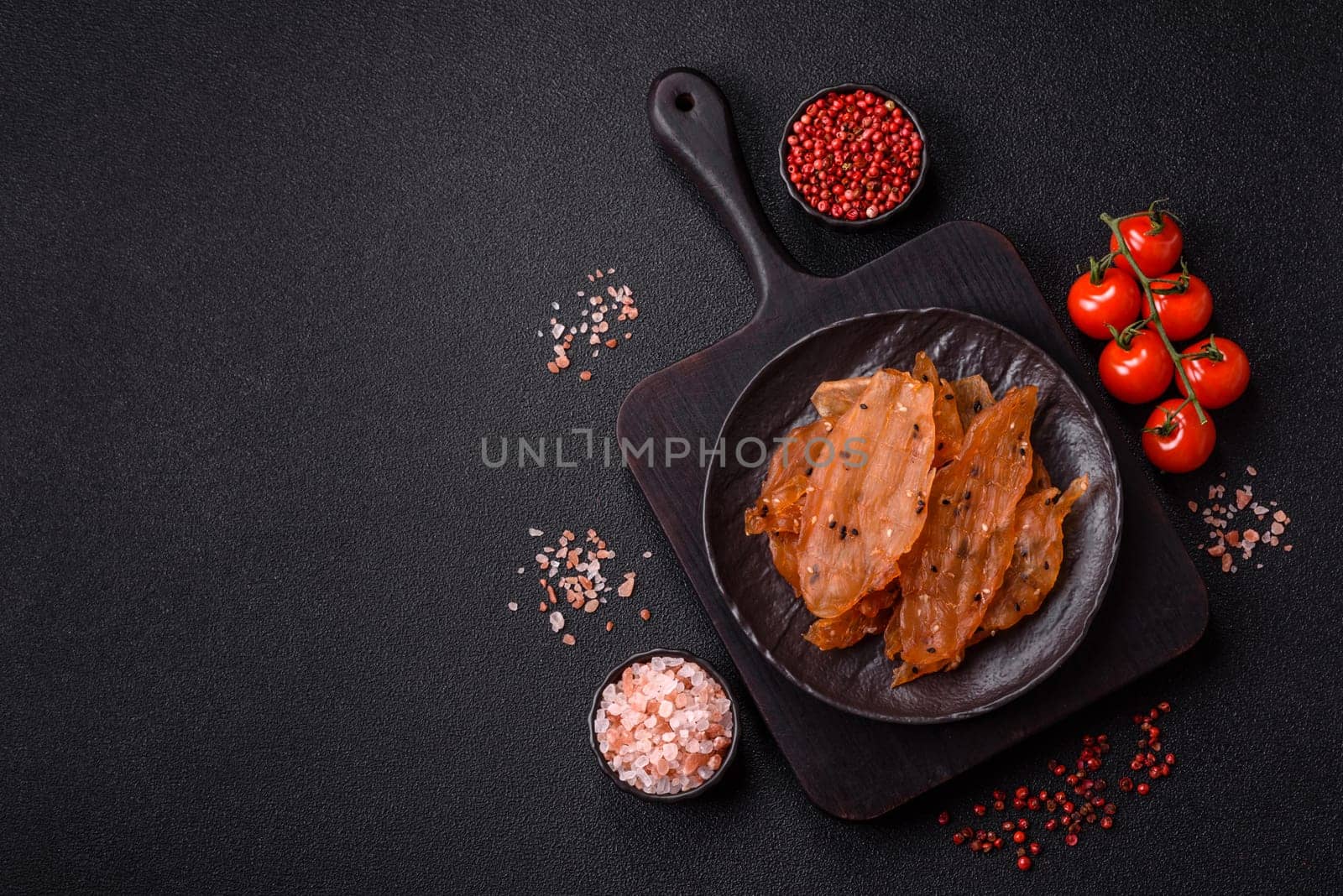 Jerky, dried chicken meat with salt and spices on a dark concrete background
