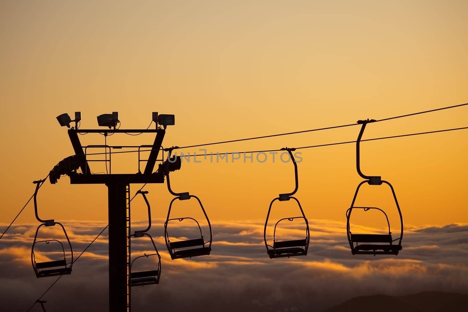 ski lift over clouds in sunset