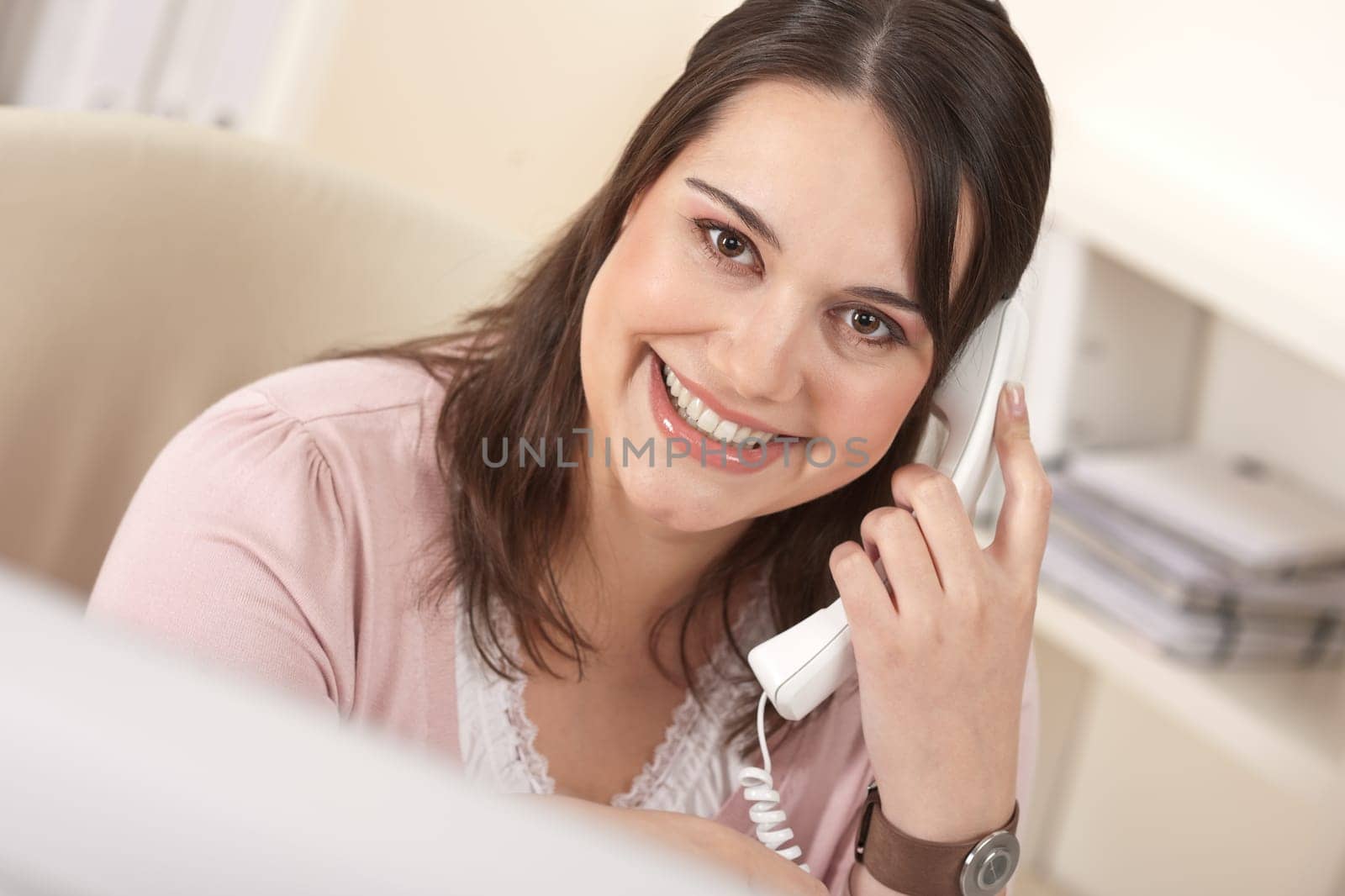 Smiling young woman on the phone at office