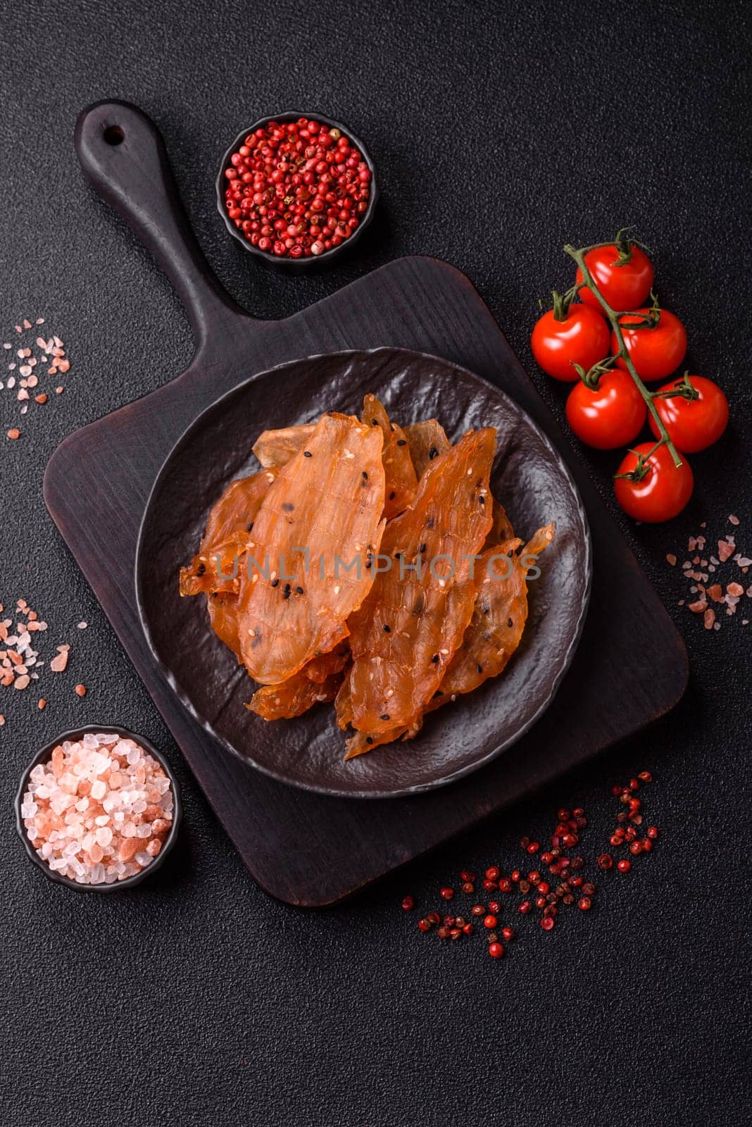 Jerky, dried chicken meat with salt and spices on a dark concrete background