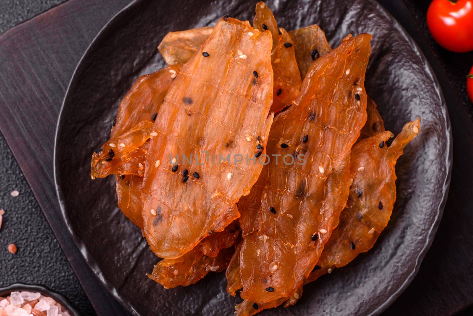 Jerky, dried chicken meat with salt and spices on a dark concrete background