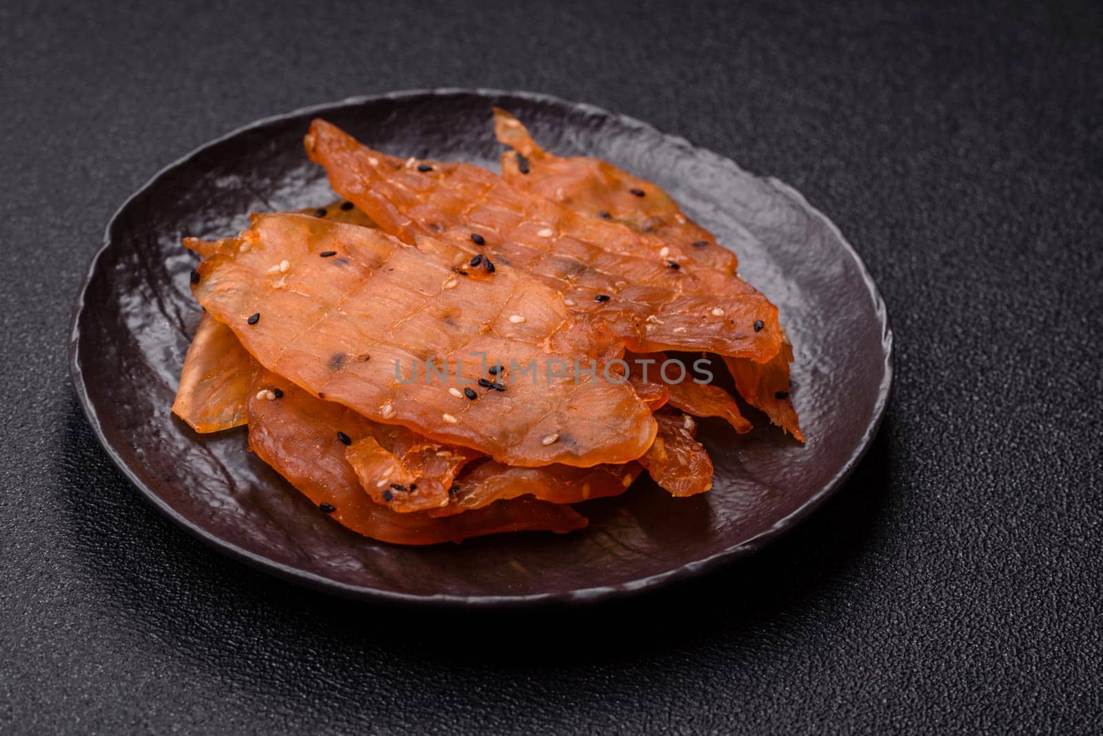 Jerky, dried chicken meat with salt and spices on a dark concrete background