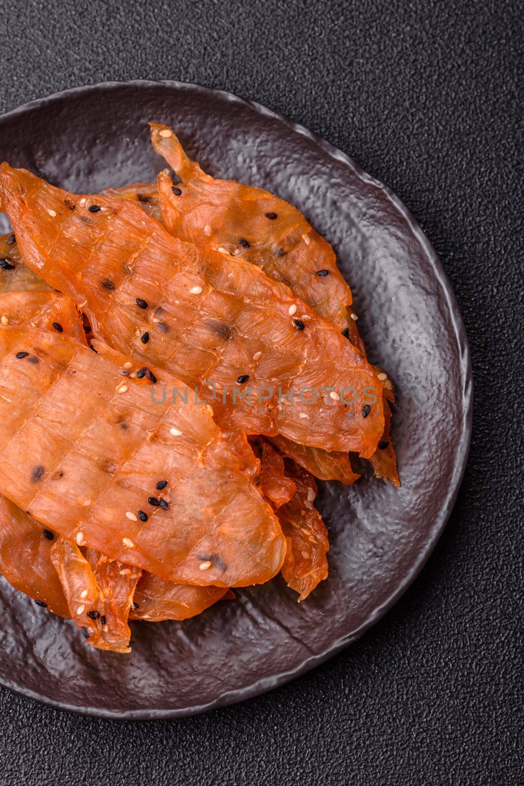 Jerky, dried chicken meat with salt and spices on a dark concrete background