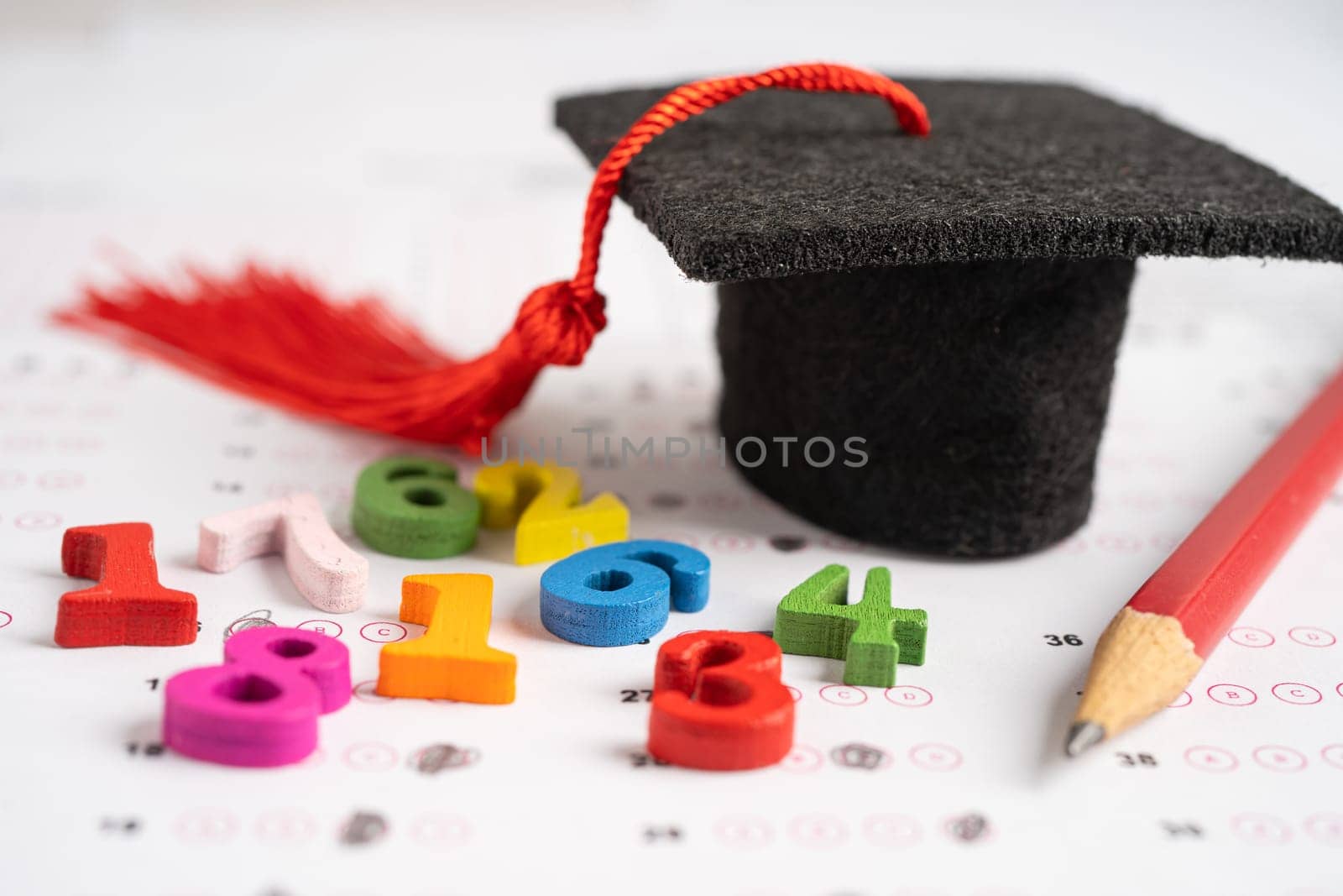 Graduation gap hat and pencil on answer sheet paper, Education study testing learning teach concept. by pamai