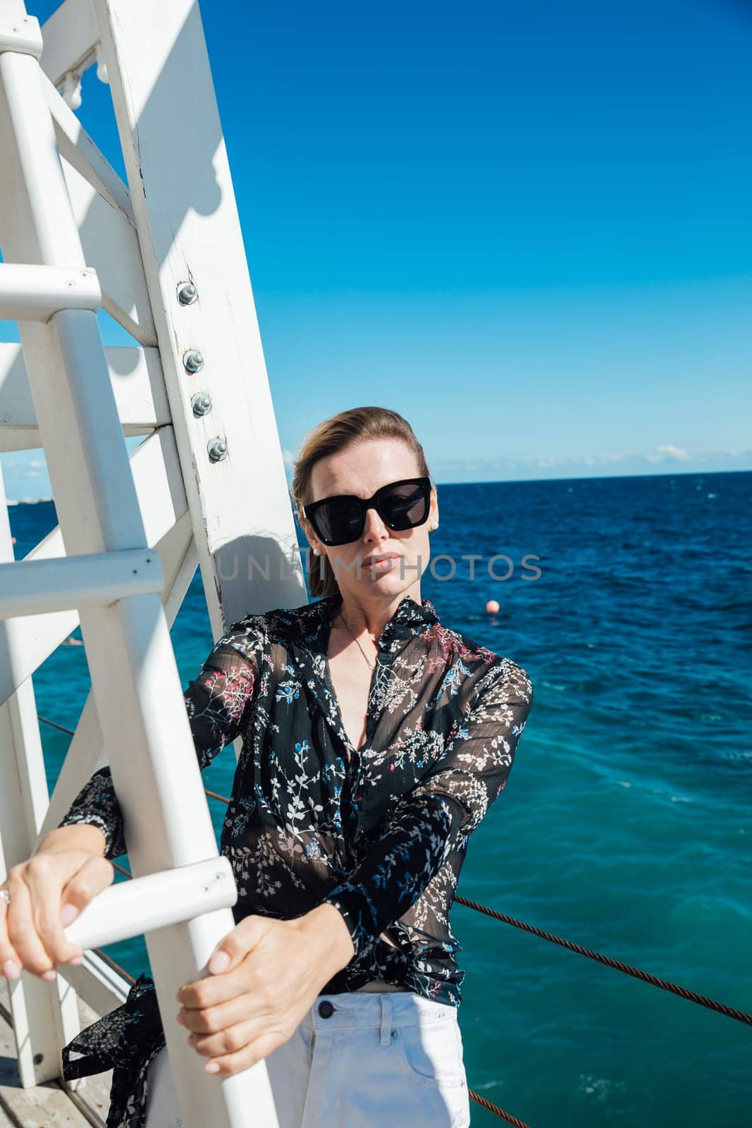 woman in sunglasses stands at the white stairs to the sea