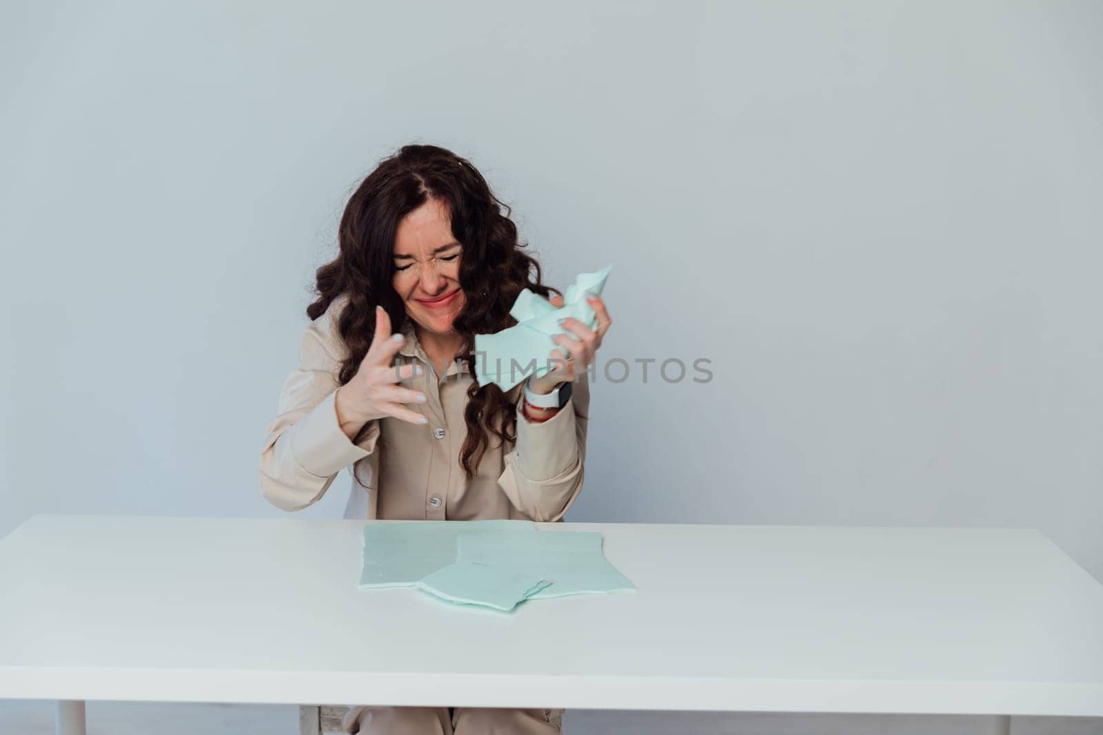 brunette woman sits at a table tearing up paper