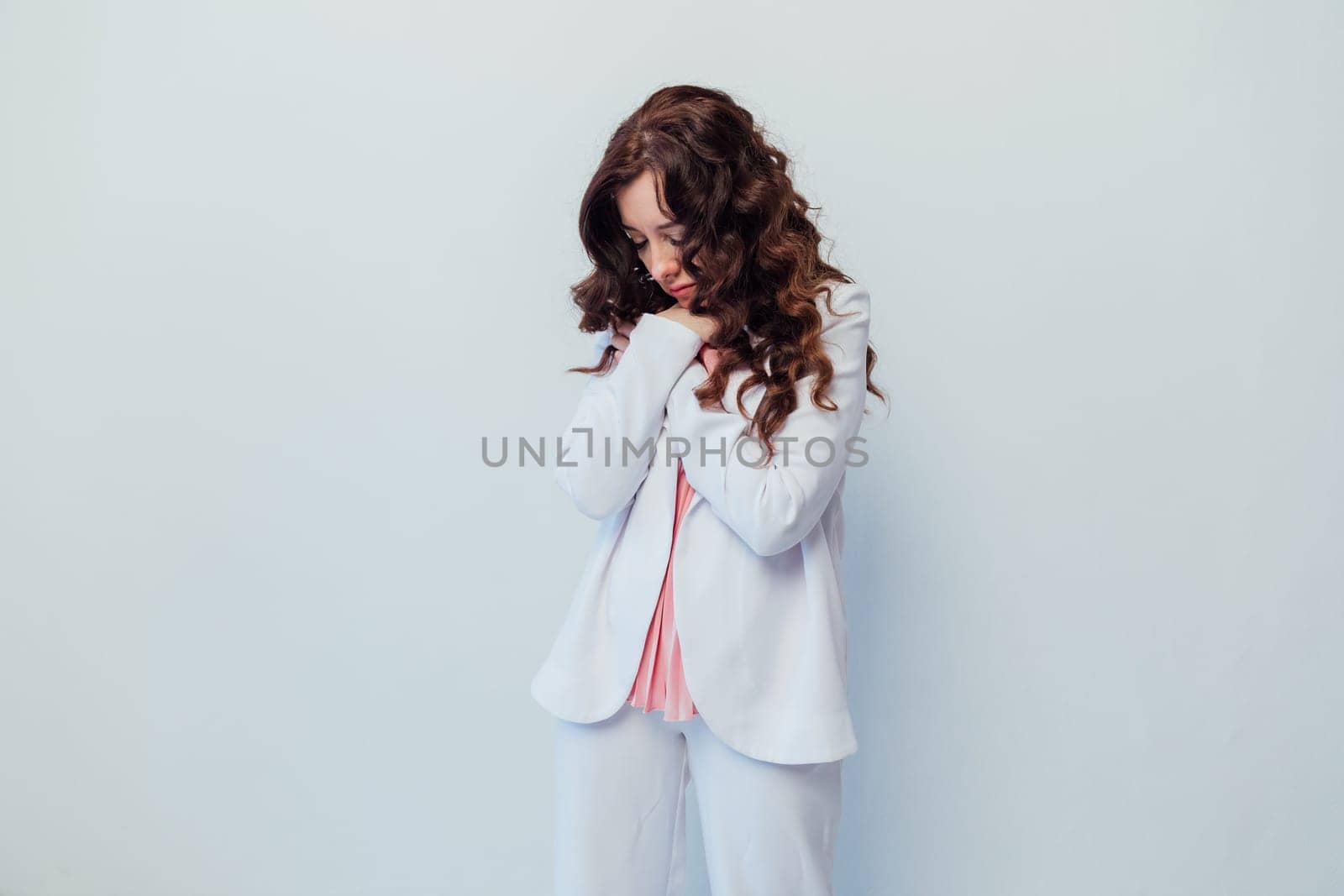 woman in a white suit stands with her head down sadness