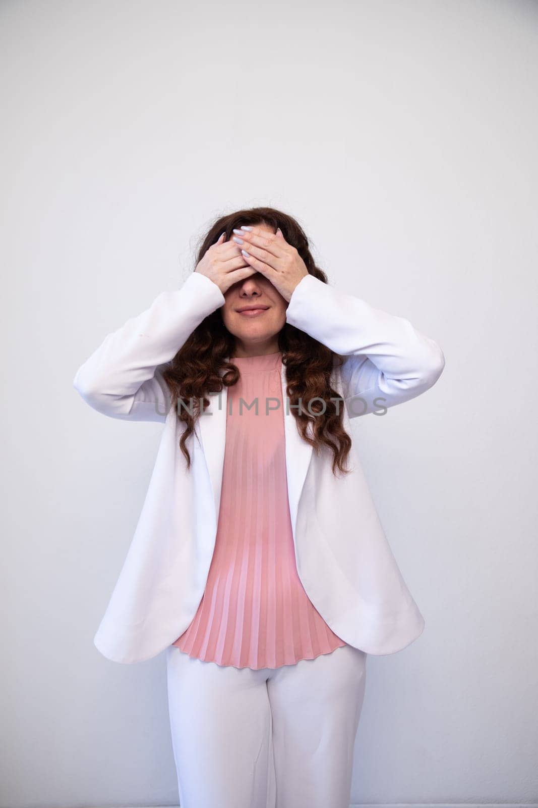 woman in a white suit covered her face with her hands