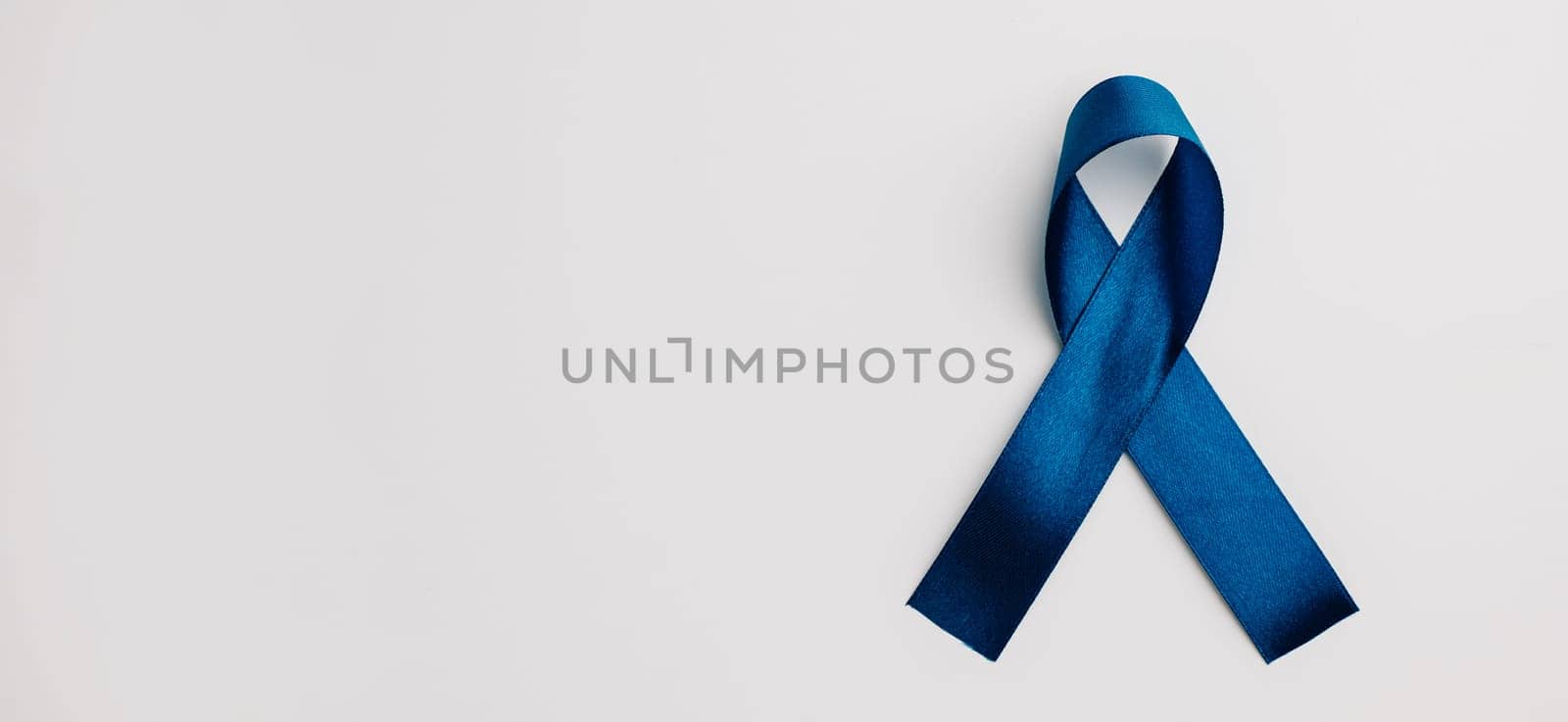 Blue satin ribbon, emblematic of world diabetes day in November, on a white background. Copy space for messages of patient support and medical care.